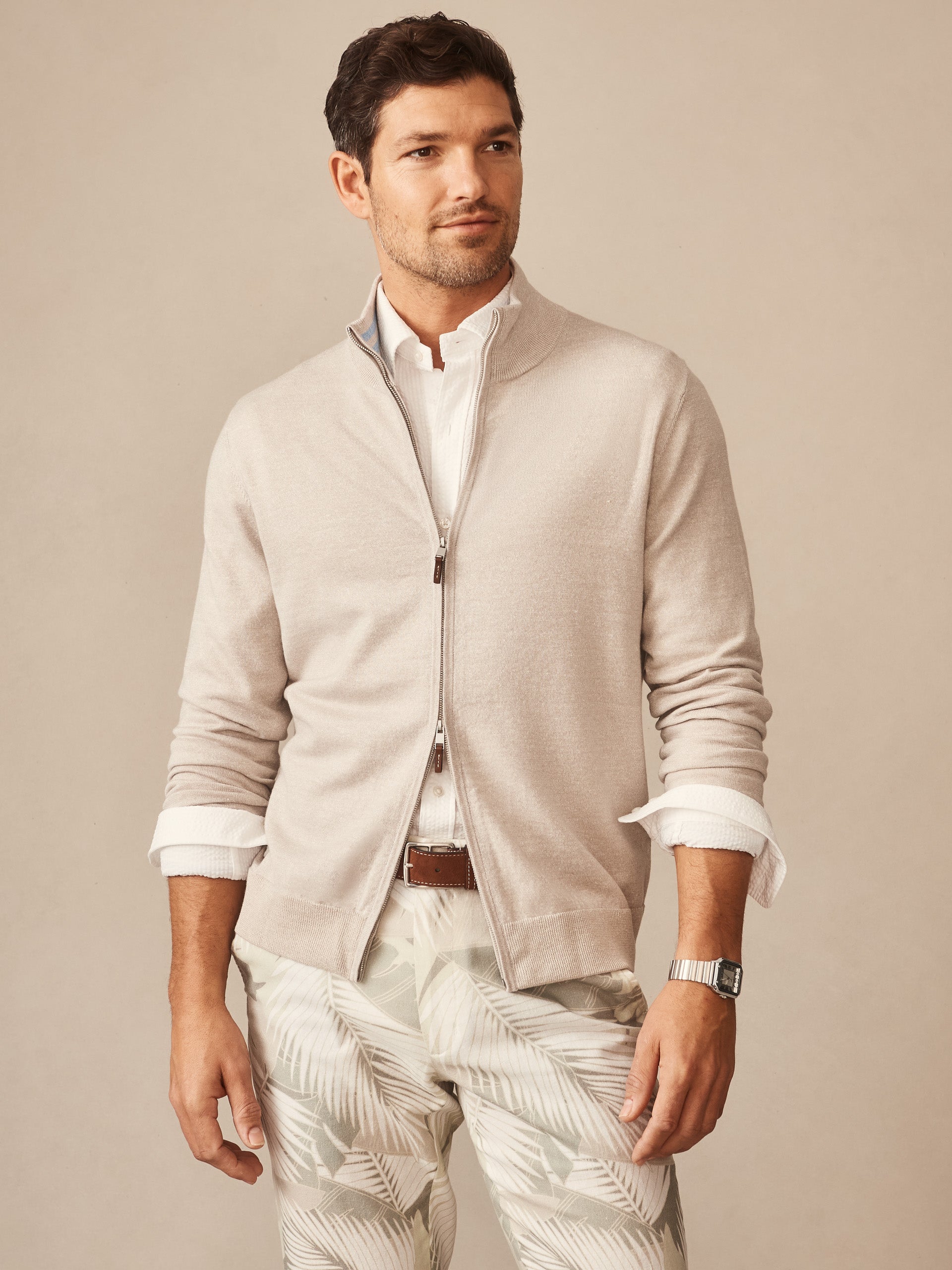 Man wearing a beige Orwell Sweater by J.McLaughlin over a white shirt, paired with light patterned pants, embodying effortlessly stylish, enduring designs and innovative fabrics from a legacy of timeless fashion. A destination for defining style. Life, Well-Lived.