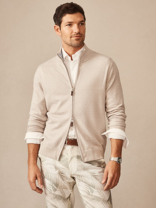 Man wearing a beige Orwell Sweater by J.McLaughlin over a white shirt, paired with light patterned pants, embodying effortlessly stylish, enduring designs and innovative fabrics from a legacy of timeless fashion. A destination for defining style. Life, Well-Lived.