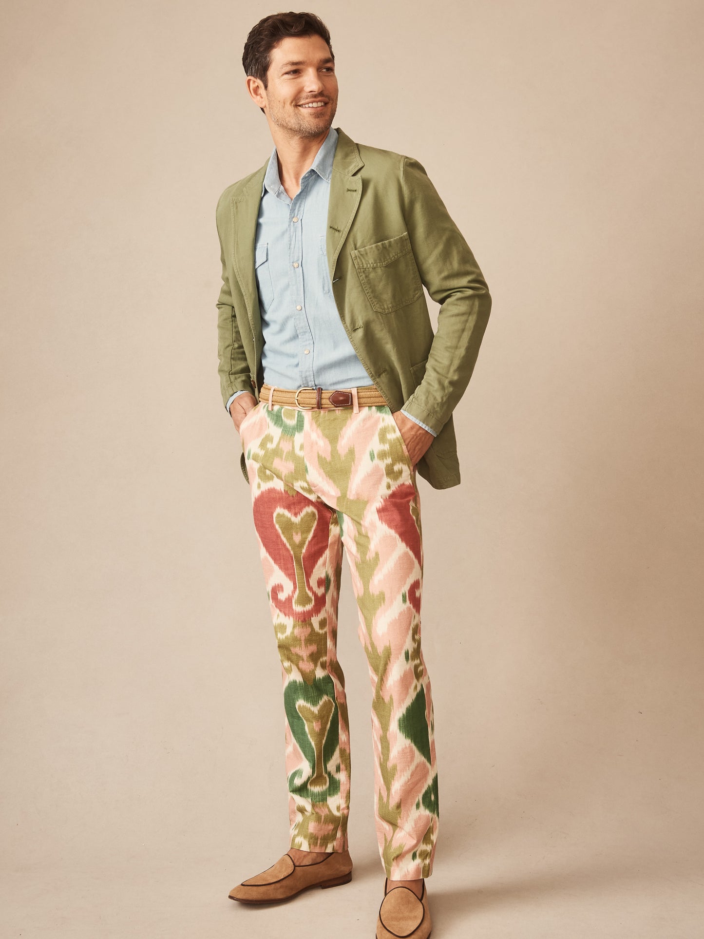 Man wearing a sage green Charlestown Jacket by J.McLaughlin paired with a light blue shirt and patterned pants in cream, green, and red, showcasing effortlessly stylish, enduring designs and innovative fabrics for a legacy of timeless fashion. A destination for defining style. Life, Well-Lived.