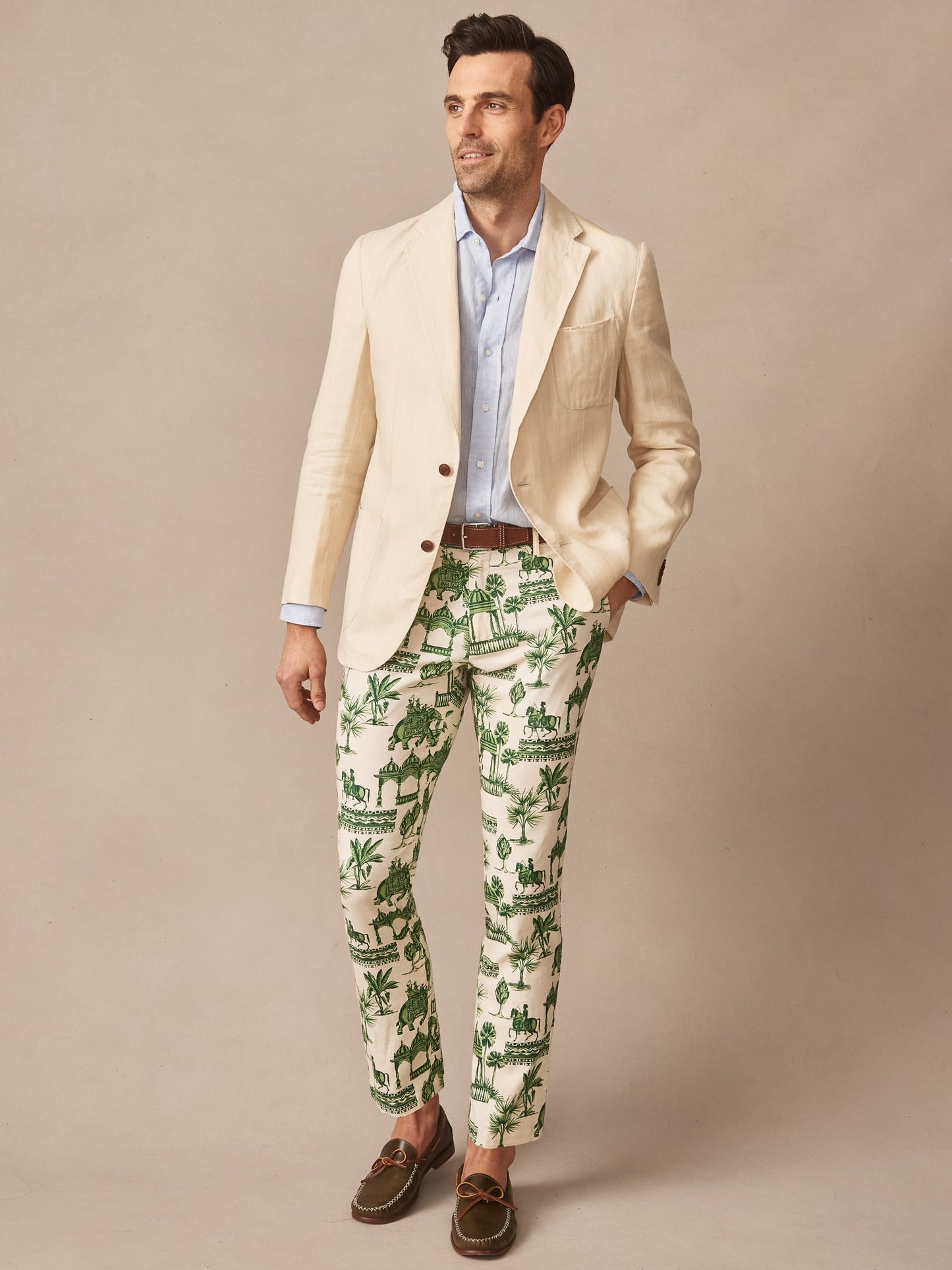 Man wearing Madison Fancy Pants in Desert Toile with green toile pattern, paired with light blue shirt, beige blazer, and brown loafers by J.McLaughlin, showcasing effortlessly stylish, enduring designs and innovative fabrics in a legacy of timeless fashion. A destination for defining style. Life, Well-Lived.