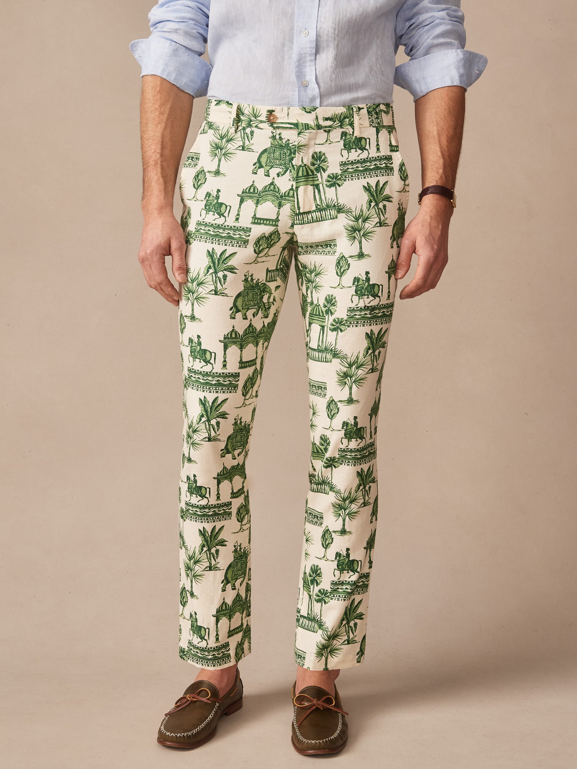 Man wearing Madison Fancy Pants in Desert Toile by J.McLaughlin, featuring green intricate desert-inspired print on light fabric, styled with classic loafers and a light blue shirt, showcasing effortlessly stylish, enduring designs with innovative fabrics in a legacy of timeless fashion. A destination for defining style. Life, Well-Lived.