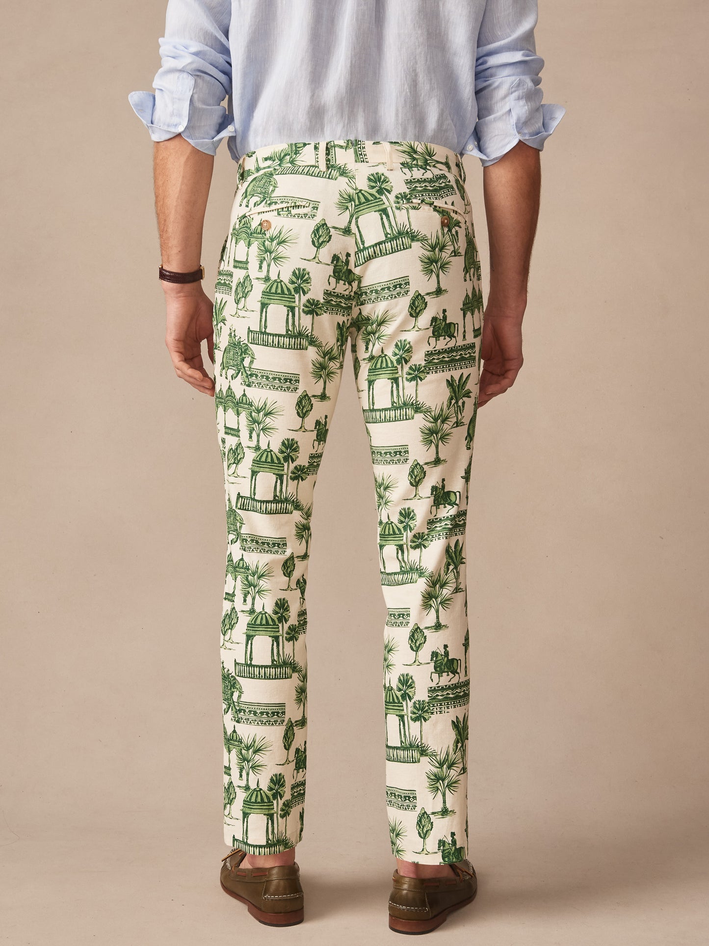 Man wearing tailored Madison Fancy Pants in Desert Toile by J.McLaughlin with green toile pattern, paired with light blue shirt and brown shoes, showcasing effortlessly stylish, enduring designs in innovative fabrics. A destination for defining style. Life, Well-Lived.