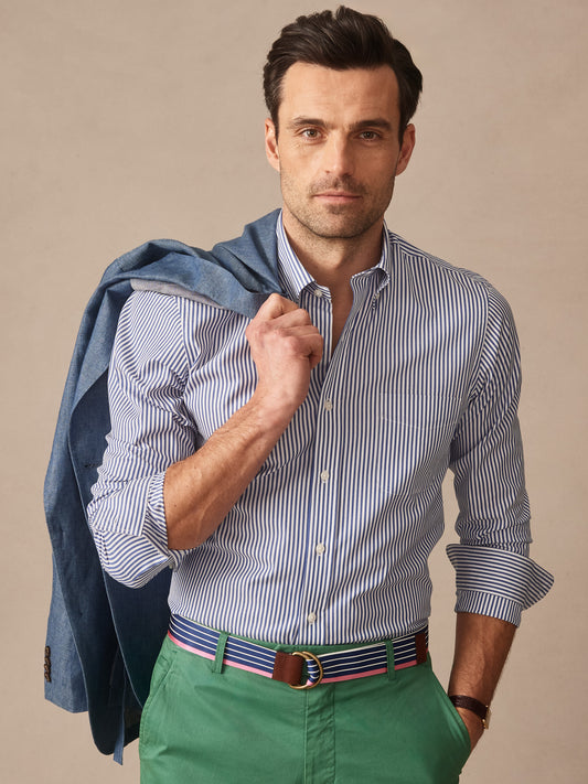Man wearing a Belvedere Cotton Shirt in Bengal Stripe by J.McLaughlin paired with green pants and a blue jacket draped over his shoulder, showcasing effortlessly stylish, enduring designs in innovative fabrics—a destination for defining style. Life, Well-Lived.