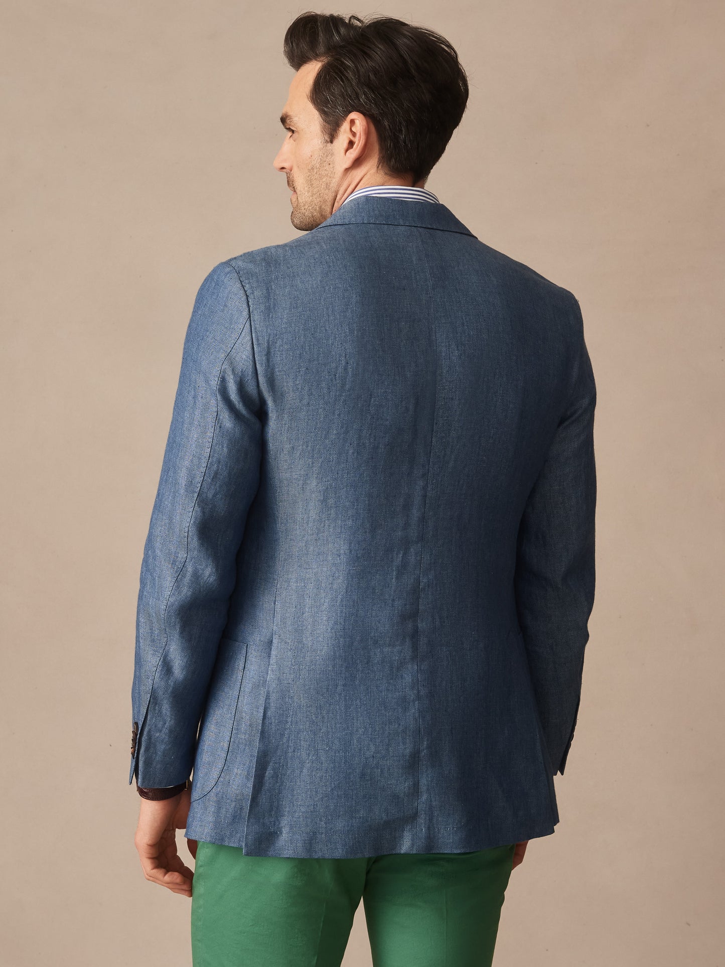 Man wearing a blue Brera Linen Sport Coat in Herringbone from J.McLaughlin, paired with green pants, showcasing effortlessly stylish, enduring designs and innovative fabrics, a destination for defining style. Life, Well-Lived.