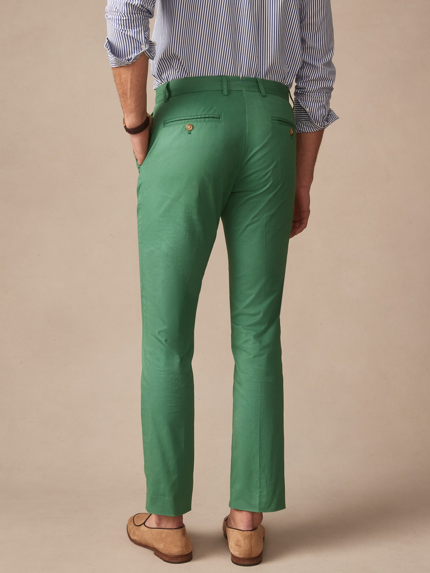 Back view of a man wearing green Madison Pants by J.McLaughlin paired with a striped shirt and tan leather shoes, showcasing effortlessly stylish and enduring designs with innovative fabrics.