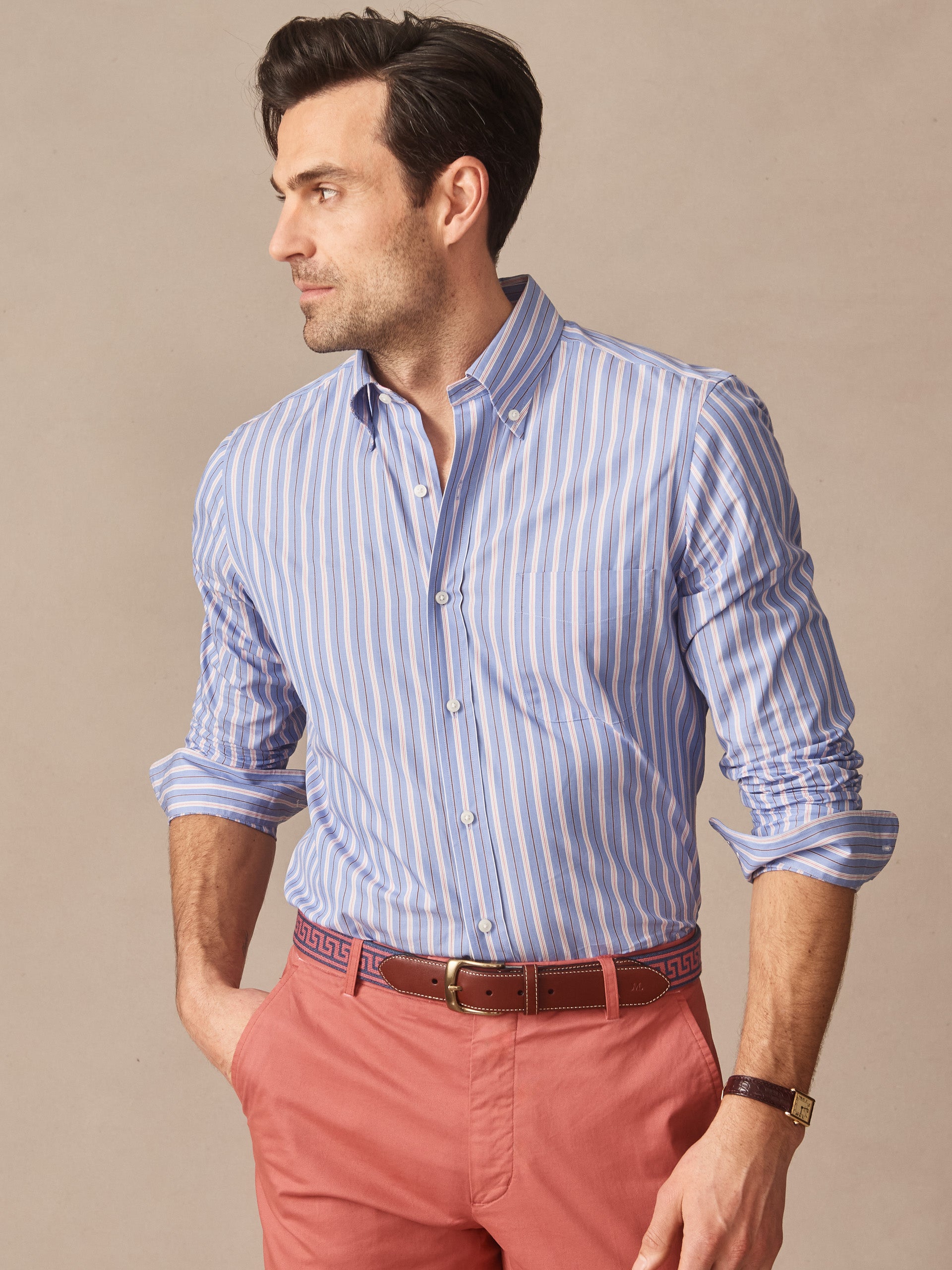 Man wearing a Belvedere Cotton Shirt in Multi Stripe with blue and white vertical stripes paired with red pants and a brown belt, showcasing J.McLaughlin’s effortlessly stylish, enduring designs and innovative fabrics. A destination for defining style. Life, Well-Lived.