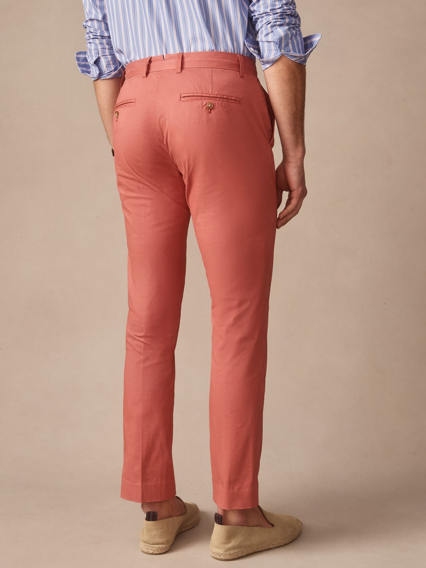 Back view of a man wearing J.McLaughlin Madison Pants in a warm red tone paired with casual shoes and a striped shirt, showcasing effortlessly stylish, enduring designs.