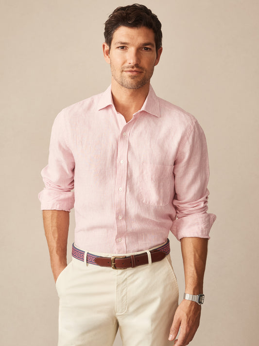Man wearing a light pink Gramercy Linen Shirt in Hairline Stripe paired with white pants and a patterned belt, showcasing J.McLaughlin’s effortlessly stylish, enduring designs.