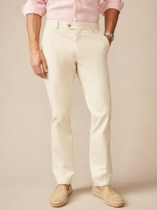 Man wearing J. McLaughlin Madison Pants in a light stone color paired with a pale pink shirt and beige slip-on shoes, showcasing effortlessly stylish and enduring designs for defining style.