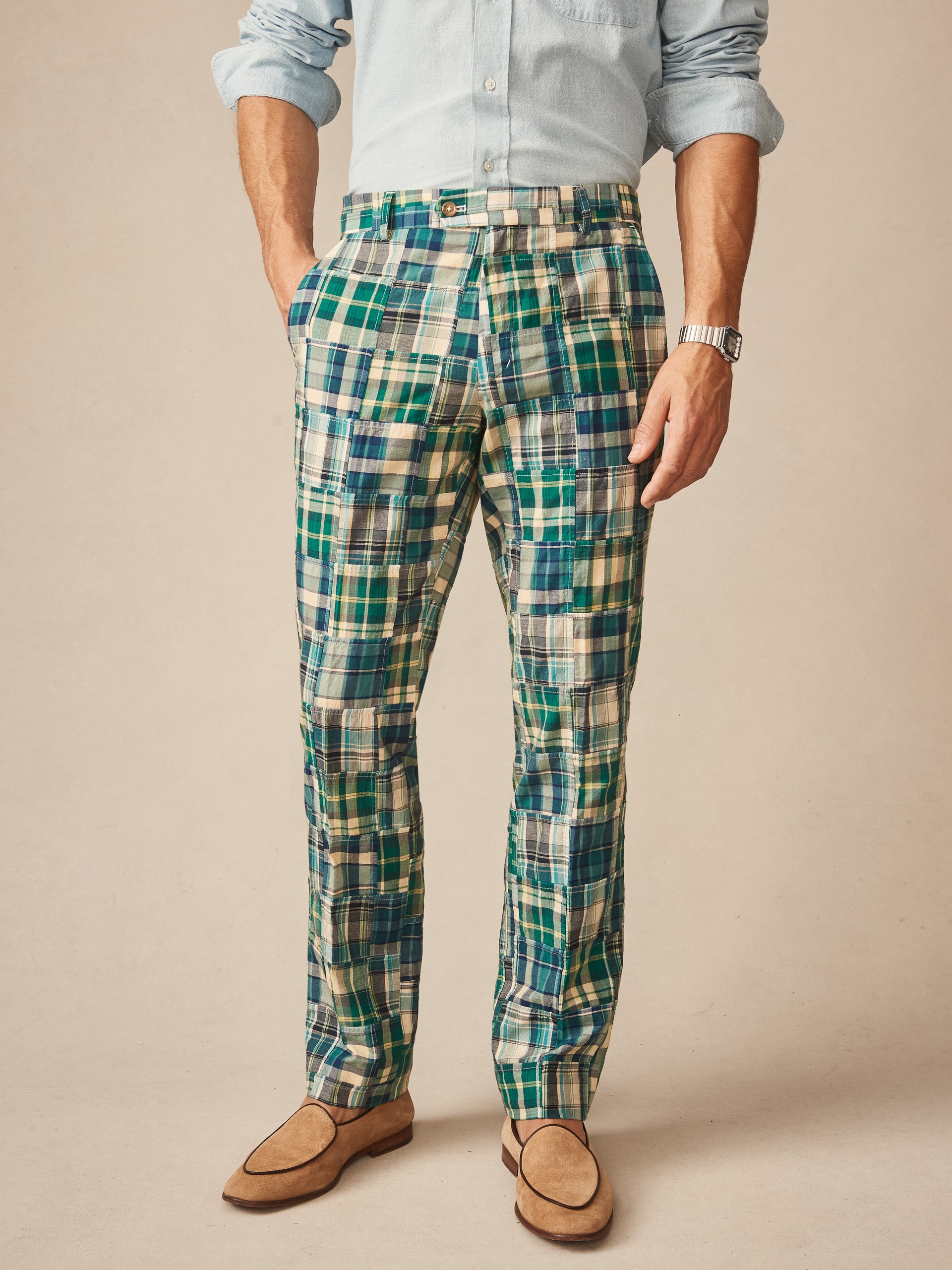 A man wearing J.McLaughlin Madison Fancy Pants in Patchwork featuring a vibrant blue and green plaid design, paired with a light blue shirt and tan loafers, showcasing effortlessly stylish, enduring designs with innovative fabrics for a legacy of timeless fashion. A destination for defining style. Life, Well-Lived.