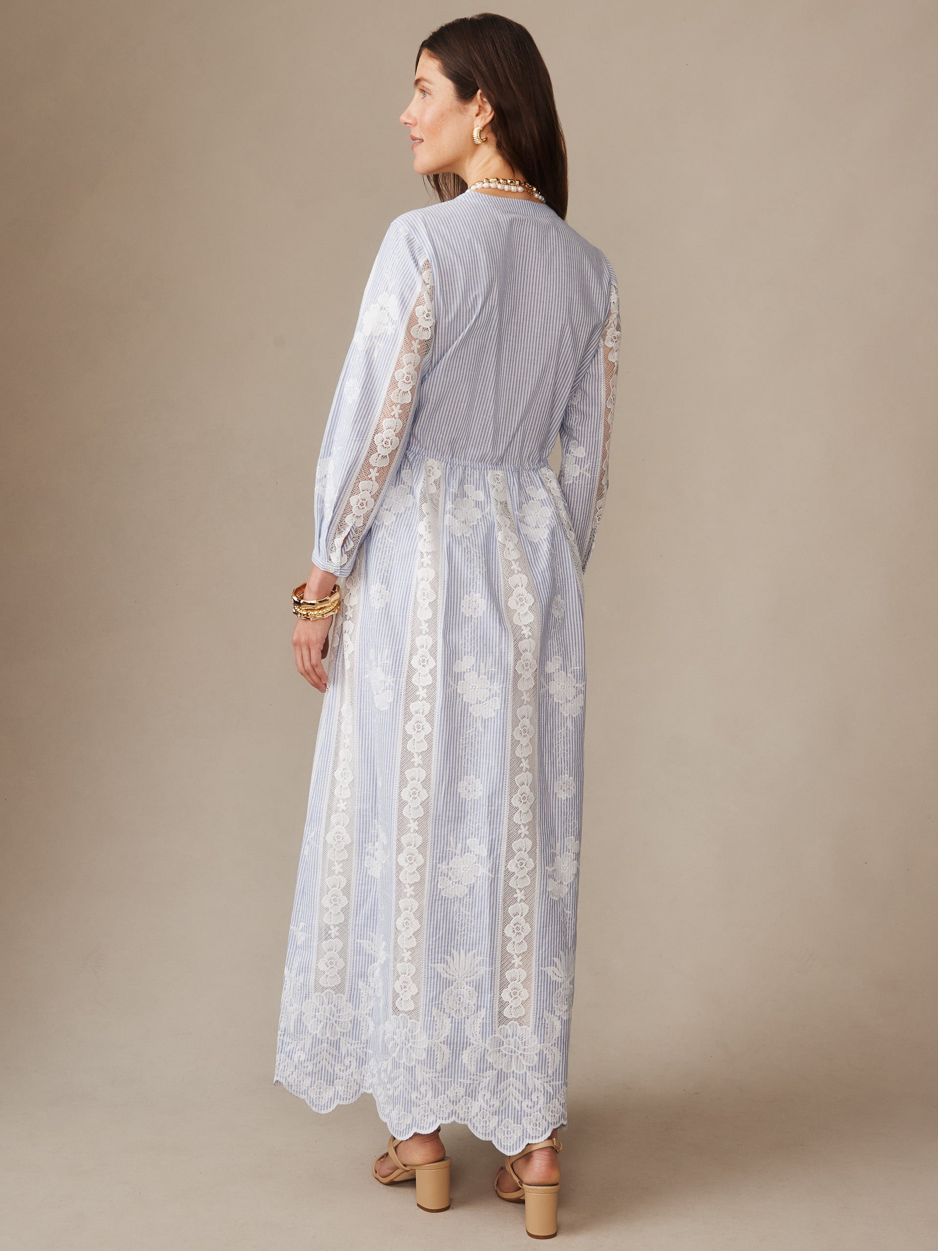 A woman wearing the Margaret Dress in Stripe by J.McLaughlin, featuring a delicate blue and white striped pattern with intricate lace detailing on the sleeves and skirt, showcasing effortlessly stylish, enduring designs with a legacy of timeless fashion, a destination for defining style. Life, Well-Lived.