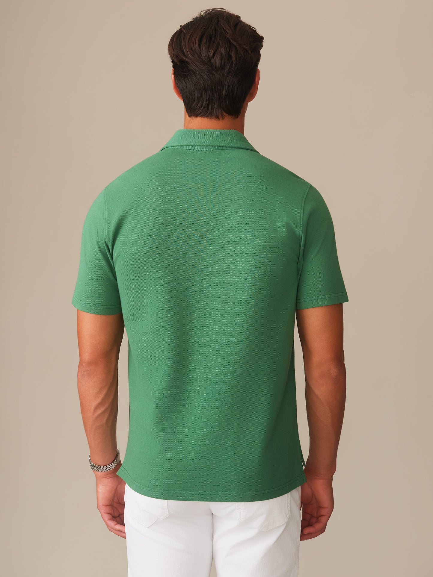 Man wearing a green Mantle Pique Polo by J.McLaughlin, showcasing effortlessly stylish, enduring designs made with innovative fabrics, perfect for a legacy of timeless fashion.