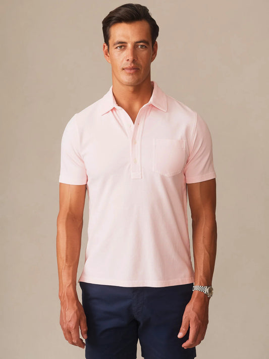 Man wearing a light pink Mantle Pique Polo by J.McLaughlin paired with dark navy pants, showcasing effortlessly stylish and enduring designs for a timeless look.