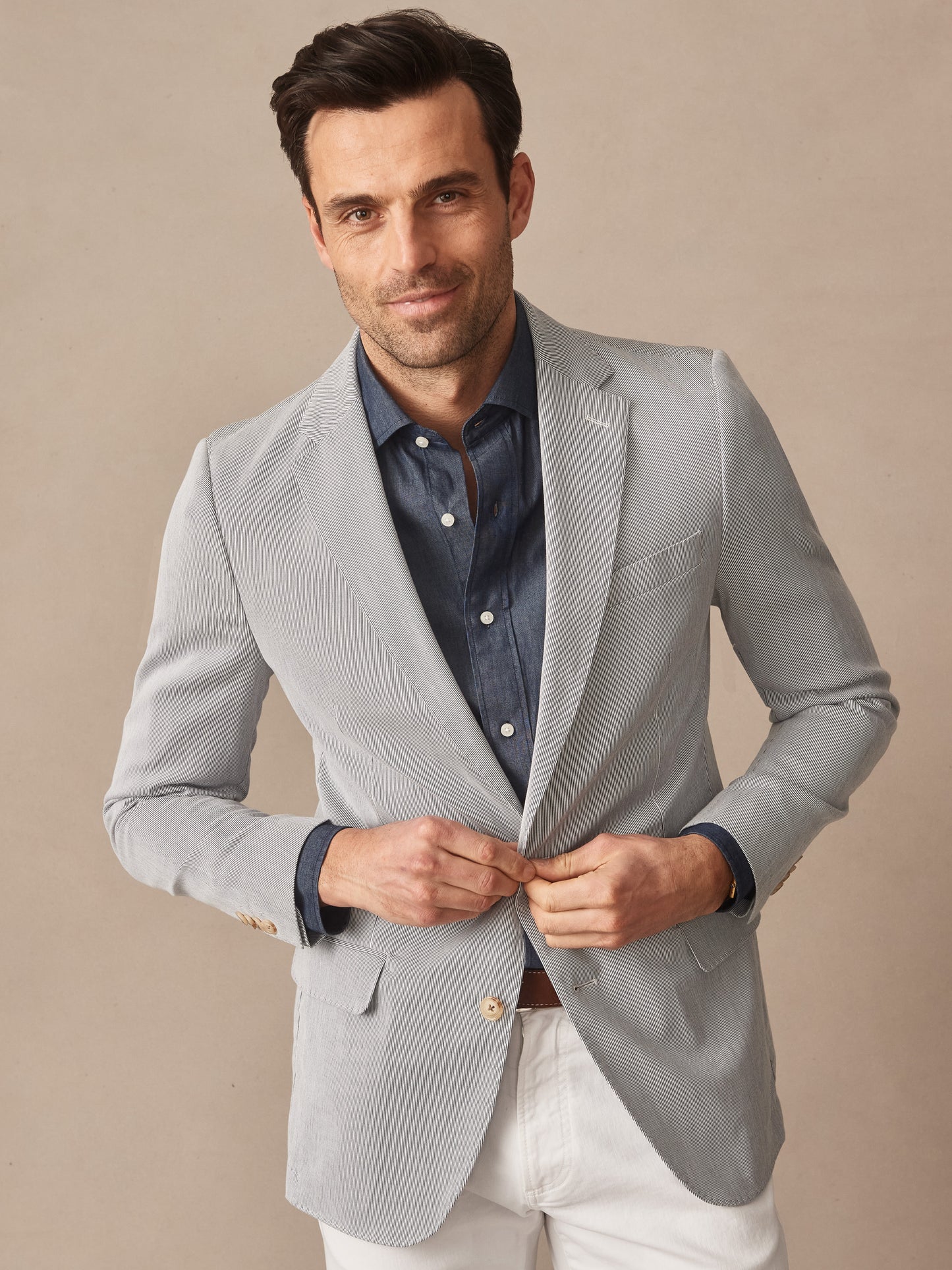 Man wearing a light gray Suffolk Sport Coat in Fineline by J.McLaughlin over a navy shirt and white pants, showcasing effortlessly stylish and enduring designs for a life well-lived.