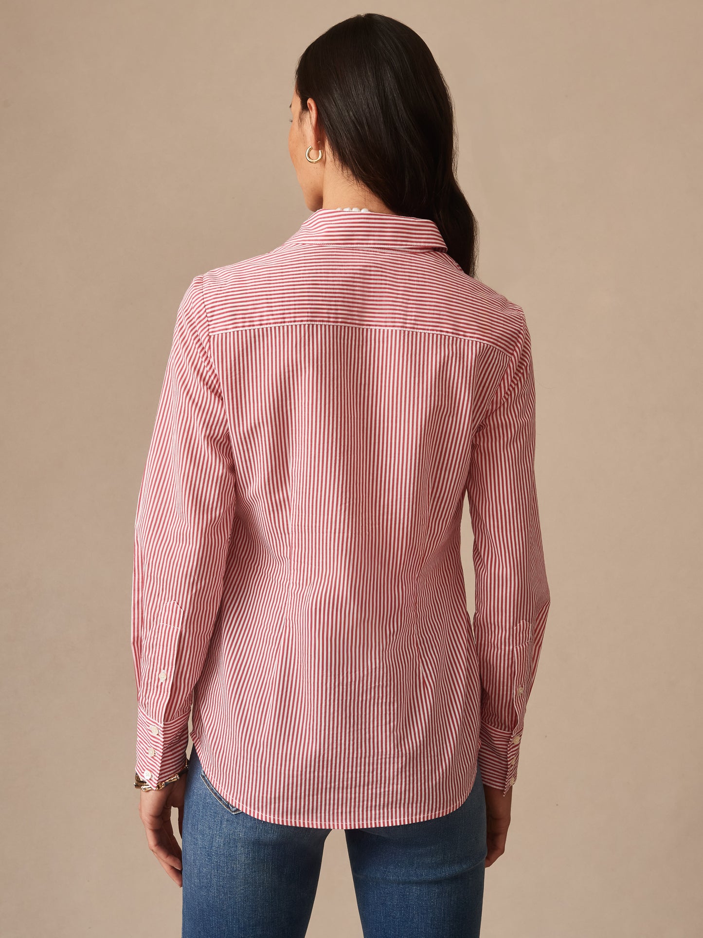 A rear view of a woman wearing the Margaux Shirt in Stripe by J.McLaughlin, featuring classic red and white stripes in an effortlessly stylish design that embodies enduring designs and the legacy of timeless fashion at a destination for defining style. Life, Well-Lived.