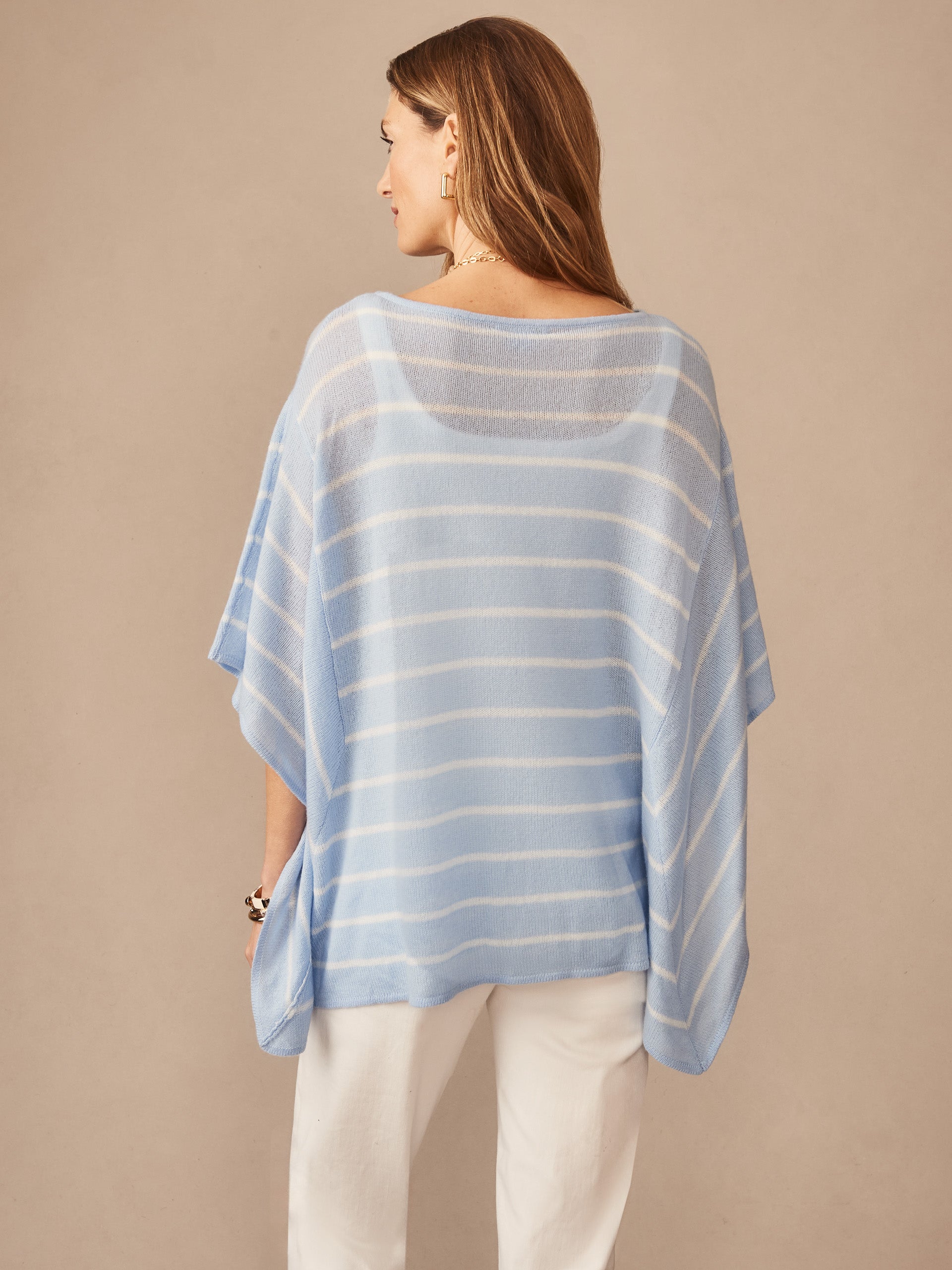 Woman wearing J.McLaughlin Marin Cashmere Poncho in Stripe, featuring soft blue and white stripes, embodying effortlessly stylish, enduring designs with innovative fabrics.