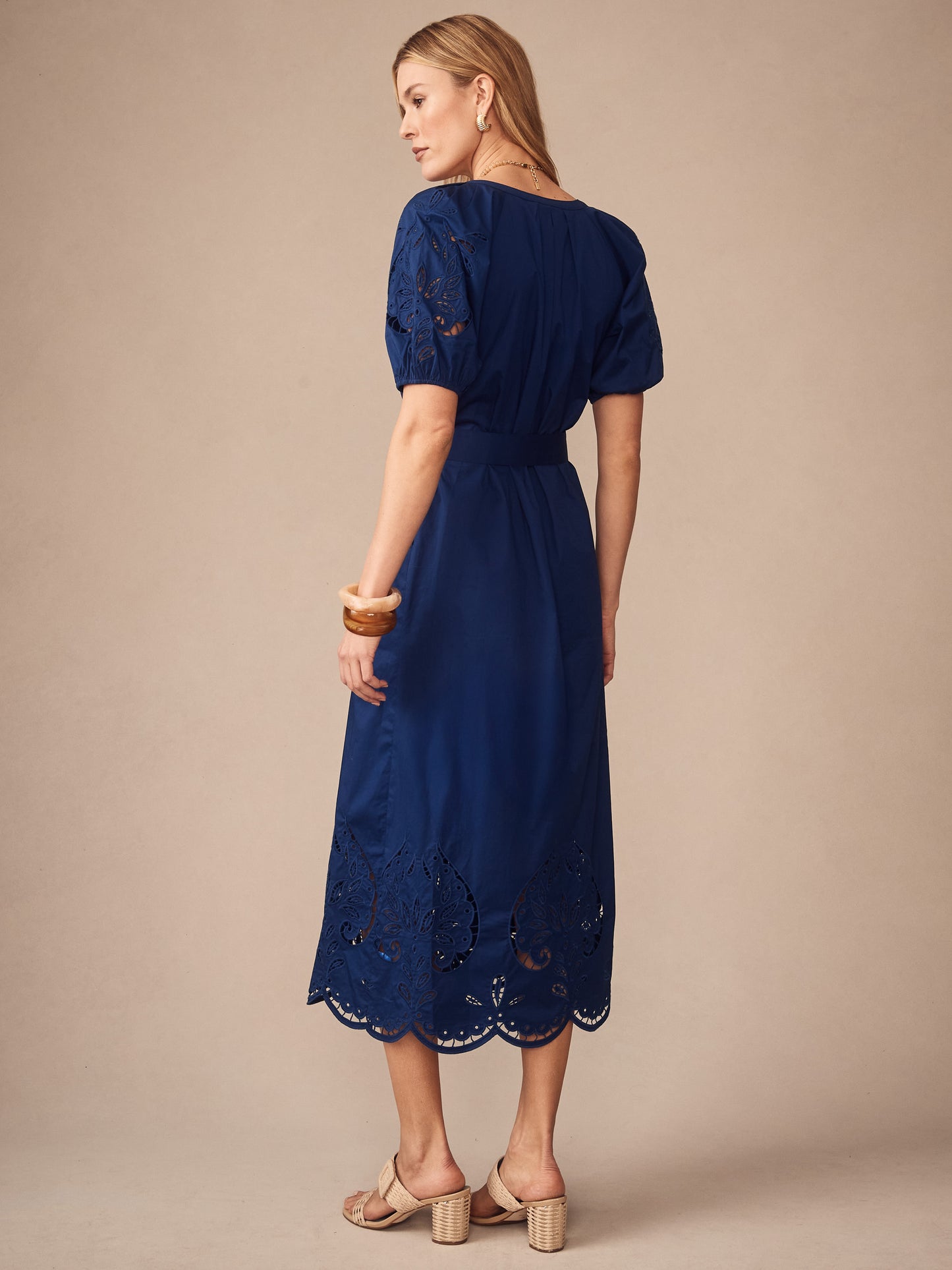 A woman wearing the Marley Embroidered Dress by J.McLaughlin in a deep navy shade with intricate embroidery on the sleeves and hem, embodying effortlessly stylish, enduring designs and a legacy of timeless fashion. A destination for defining style. Life, Well-Lived.
