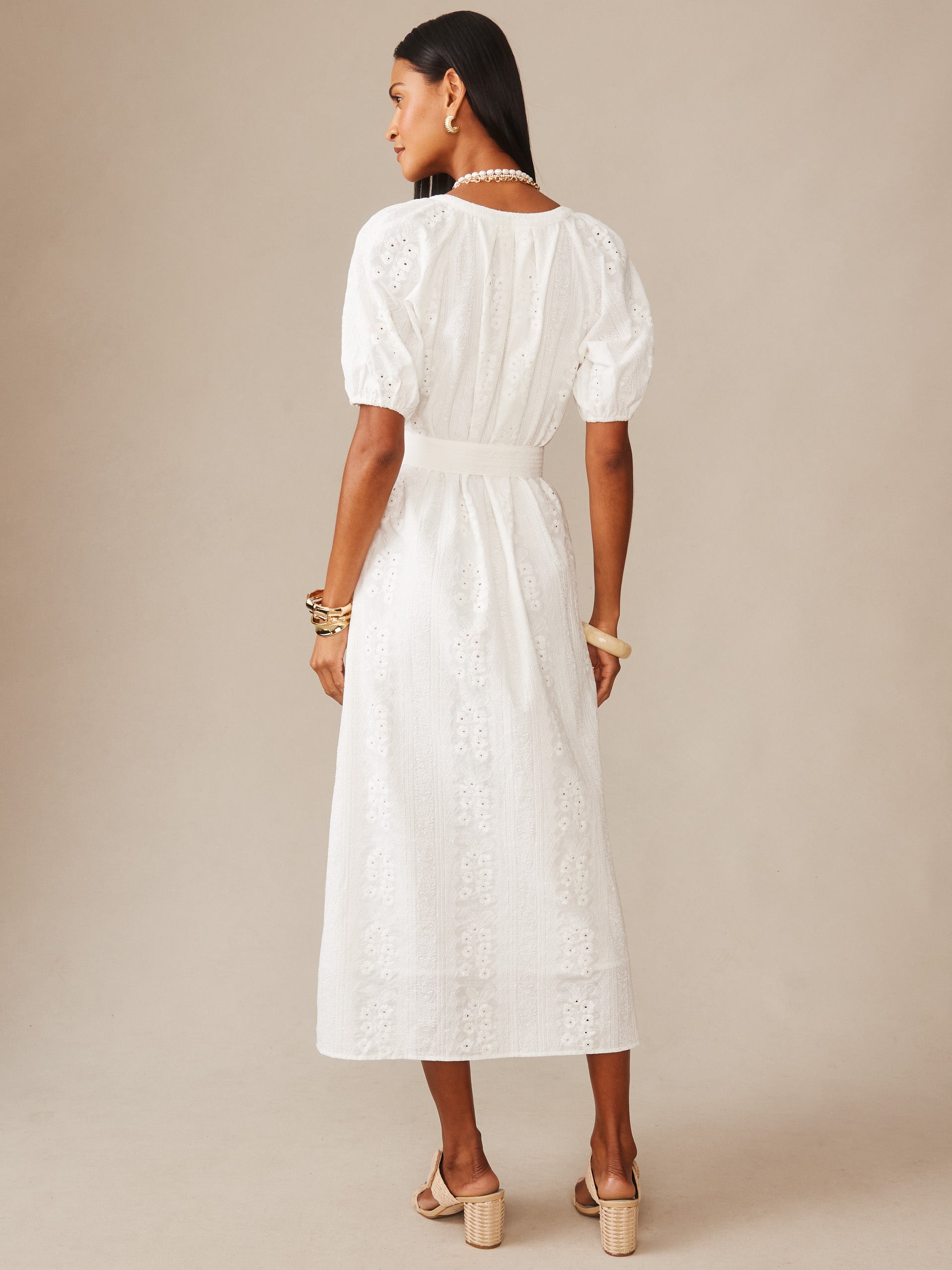 Woman modeling a white Marley Eyelet Dress by J.McLaughlin, featuring puff sleeves and intricate eyelet embroidery, paired with elegant accessories for an effortlessly stylish look.