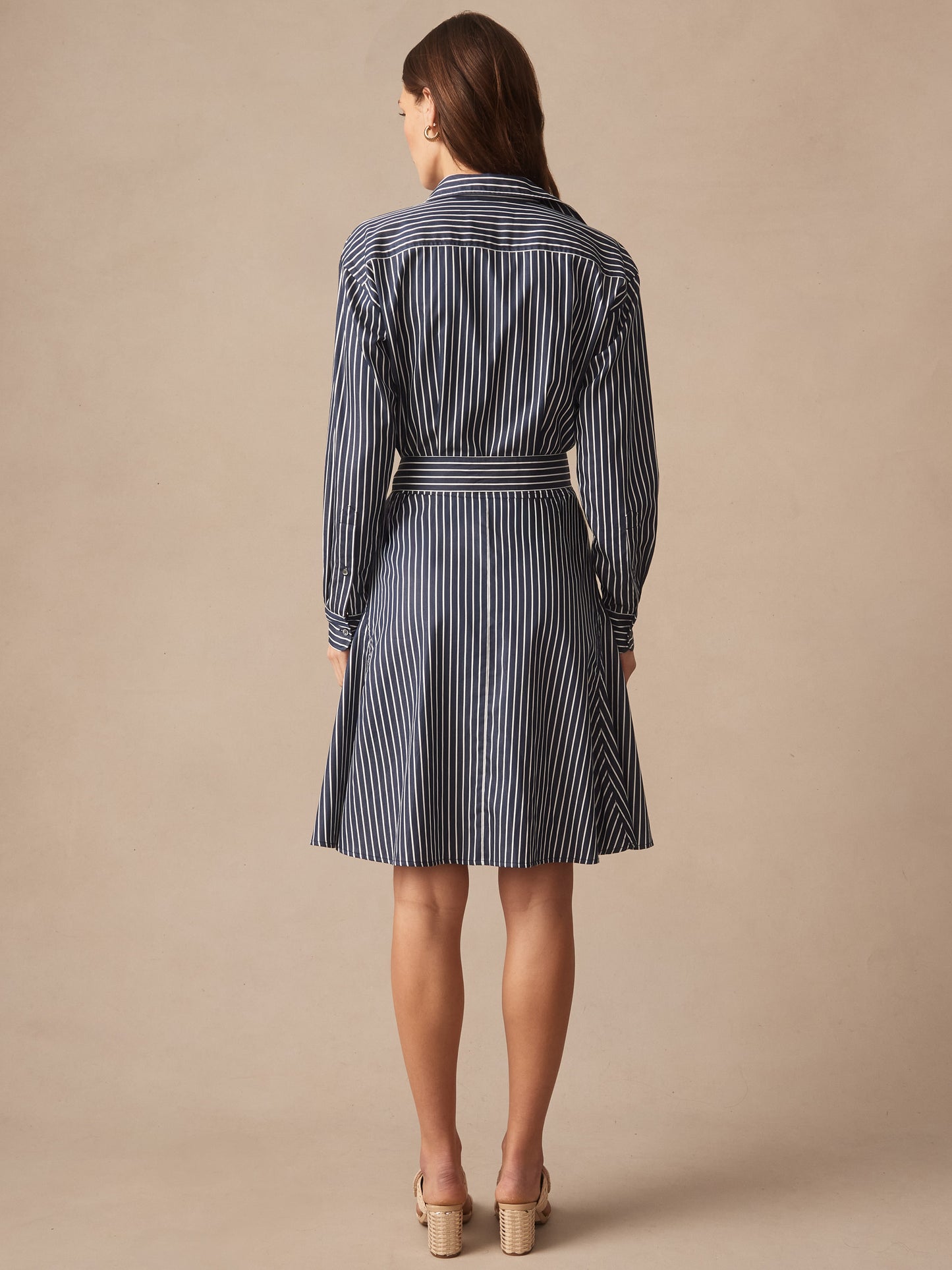 A woman wearing the Mary Dress in Stripe by J.McLaughlin, featuring a navy and white striped pattern with a belted waist, showcasing effortlessly stylish, enduring designs and innovative fabrics. A destination for defining style. Life, Well-Lived.