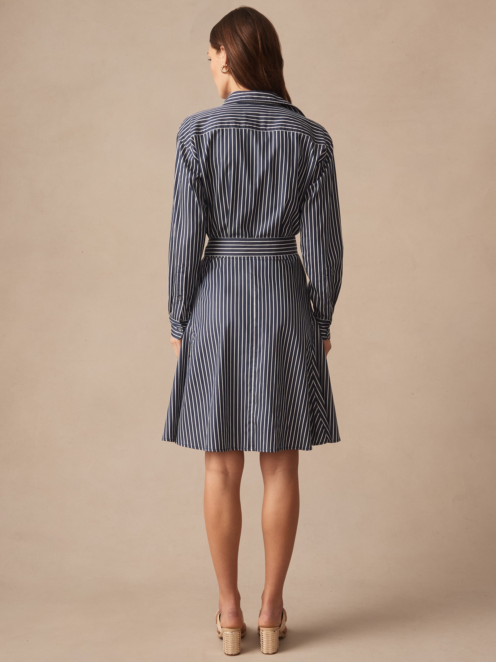 A woman wearing the Mary Dress in Stripe by J.McLaughlin, featuring a navy and white striped pattern with a belted waist, showcasing effortlessly stylish, enduring designs and innovative fabrics. A destination for defining style. Life, Well-Lived.