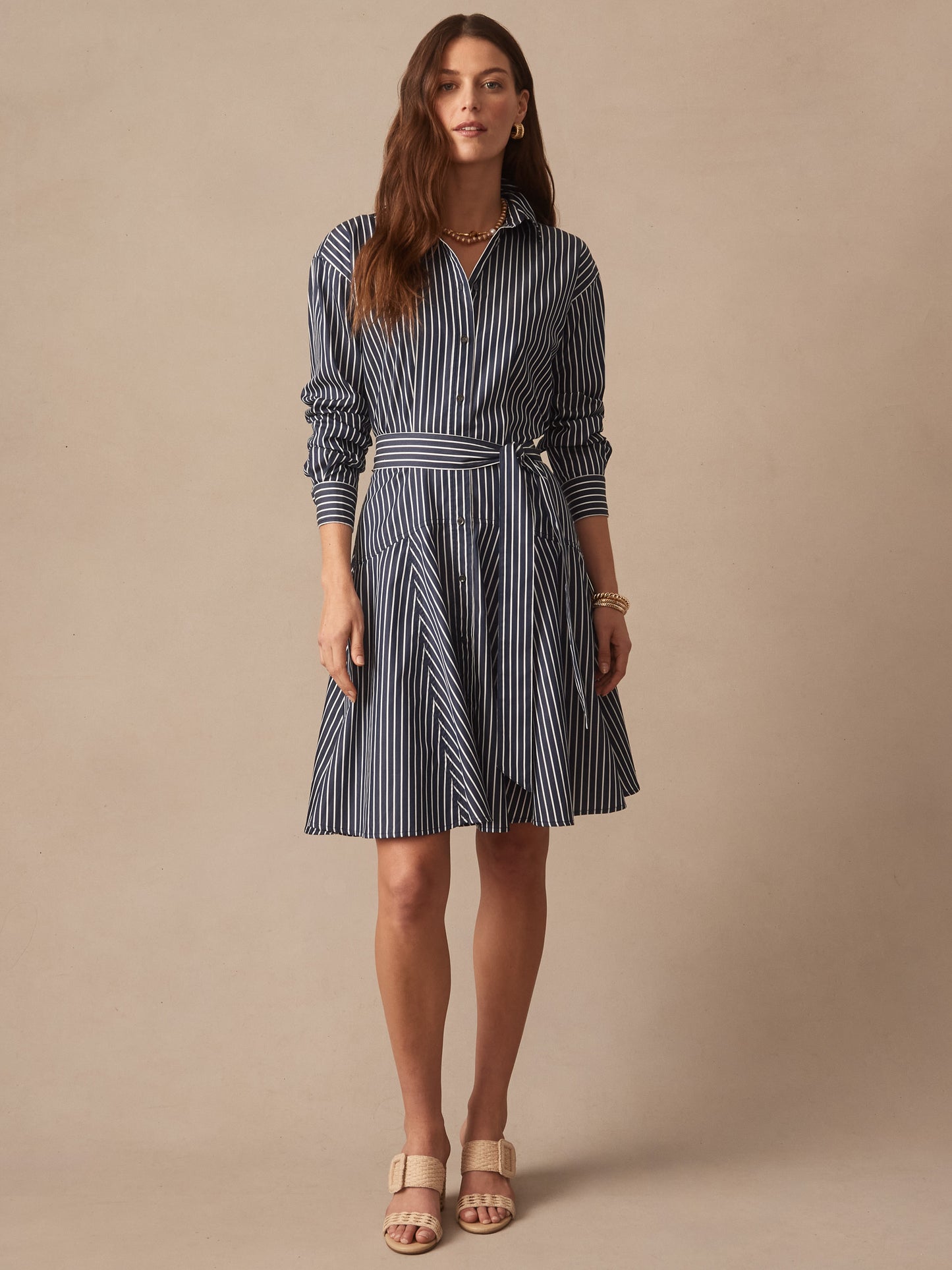 Woman wearing a navy and white striped Mary Dress in Stripe by J.McLaughlin, featuring a button-down front and a self-tie belt, showcasing effortlessly stylish, enduring designs.