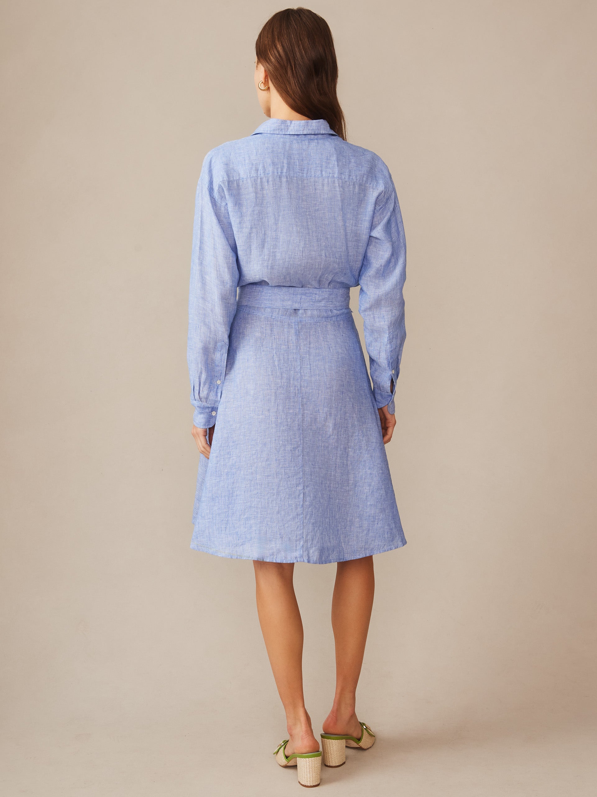 Woman wearing a light blue Mary Linen Dress in Stripe by J.McLaughlin, showcasing effortlessly stylish, enduring designs with innovative fabrics for a legacy of timeless fashion.