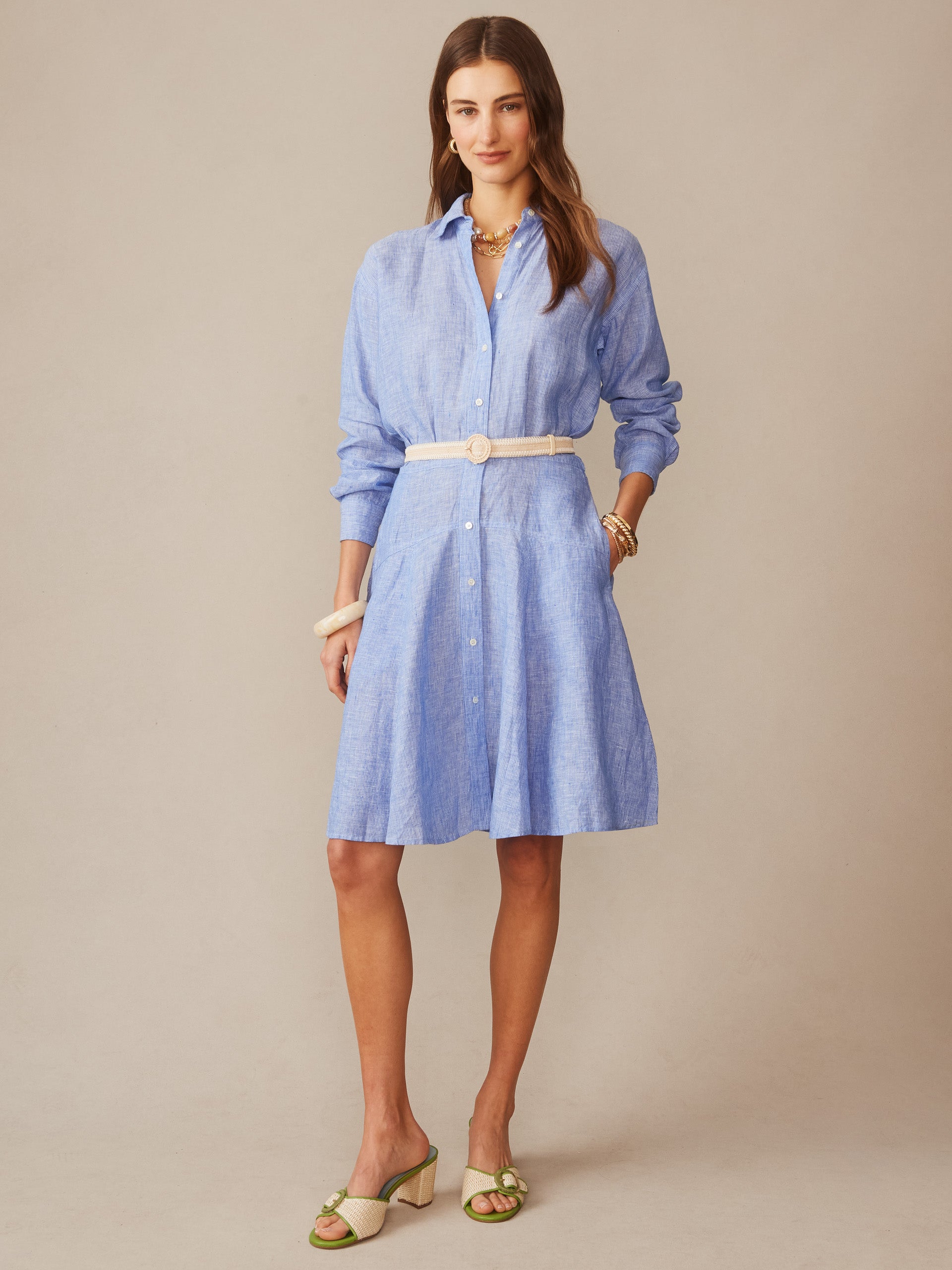 Woman wearing a light blue Mary Linen Dress in Stripe by J.McLaughlin, styled with a white belt and green sandals, showcasing effortlessly stylish, enduring designs and innovative fabrics.