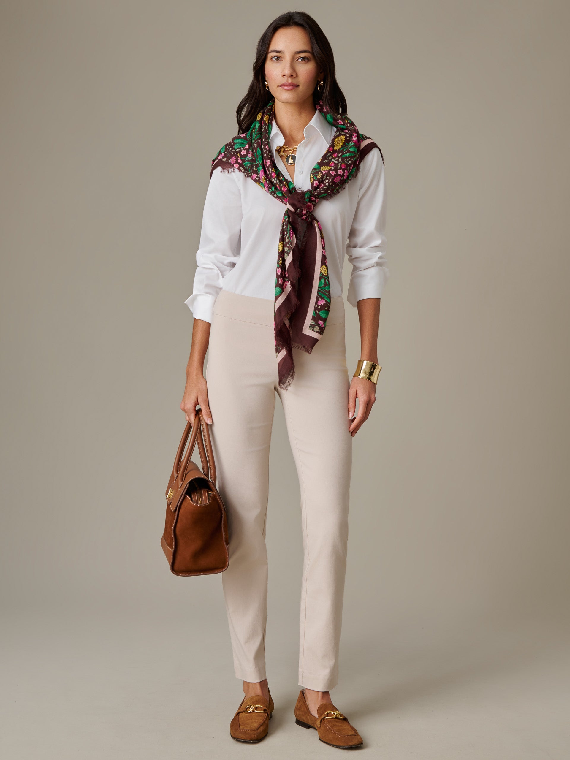Woman wearing Masie Pants by J.McLaughlin styled with a white shirt, colorful patterned scarf, brown loafers, and a brown handbag, showcasing an effortlessly stylish, timeless look.