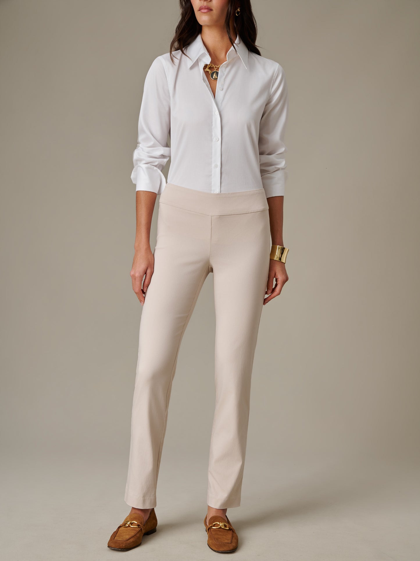 Woman wearing beige Masie Pants paired with a white button-down shirt and brown loafers, showcasing J.McLaughlin's effortlessly stylish, enduring design for timeless fashion.