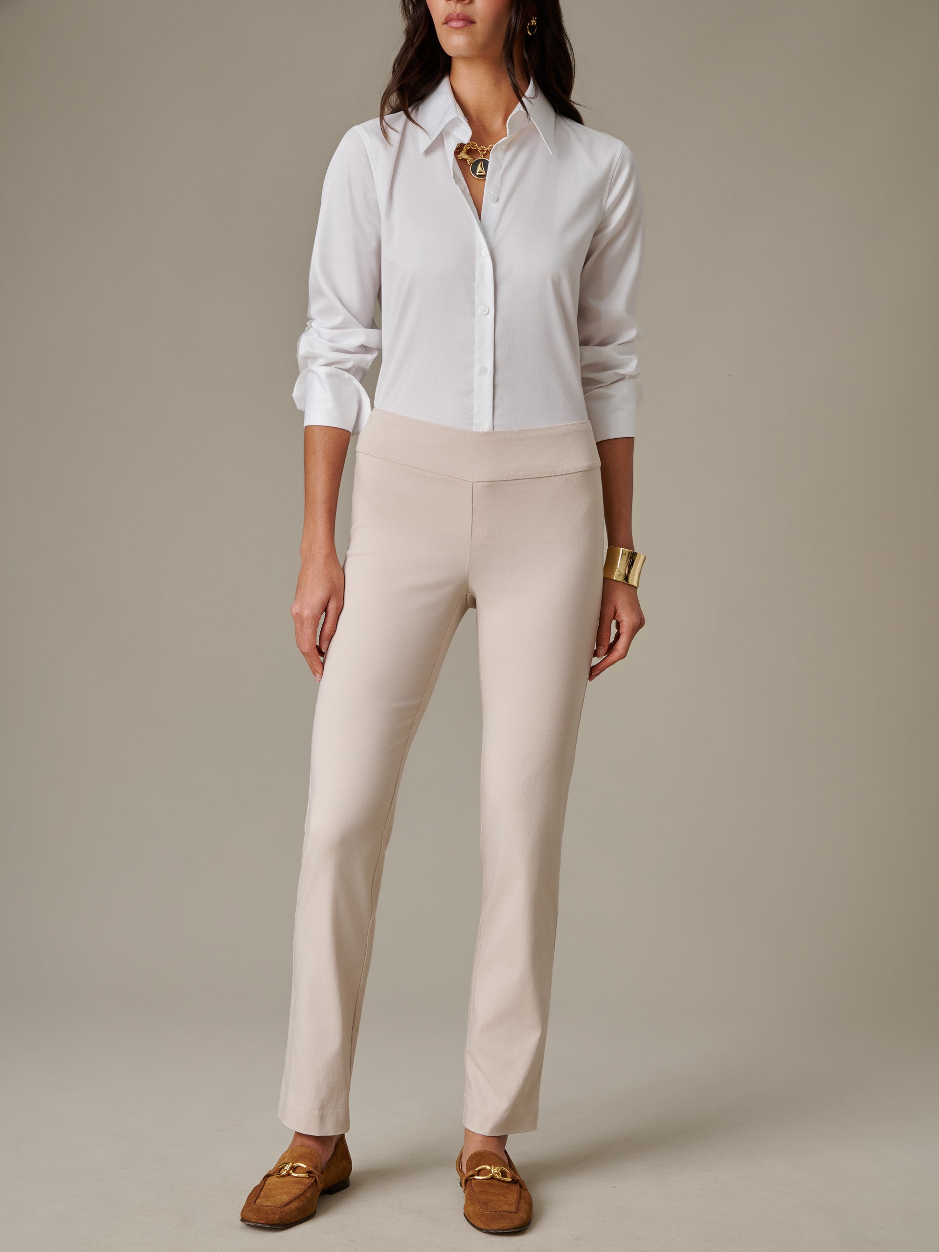 Woman wearing beige Masie Pants paired with a white button-down shirt and brown loafers, showcasing J.McLaughlin's effortlessly stylish, enduring design for timeless fashion.
