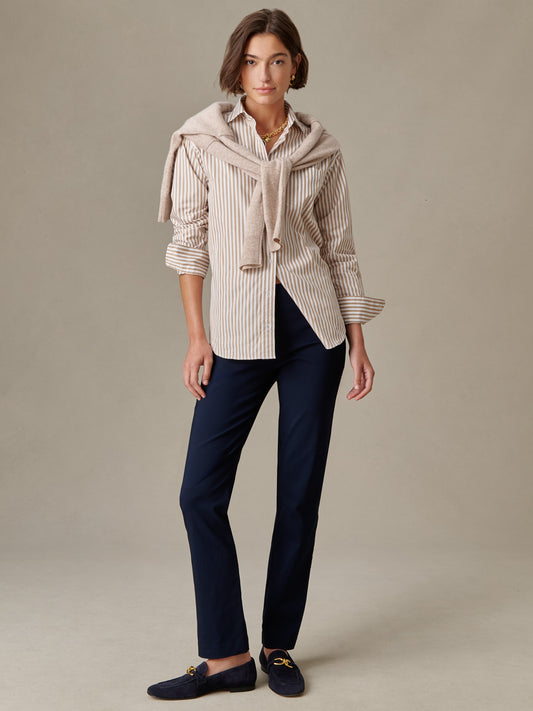 Woman wearing navy Masie Pants by J.McLaughlin paired with a beige striped shirt and light sweater draped over shoulders, showcasing effortlessly stylish, timeless design.