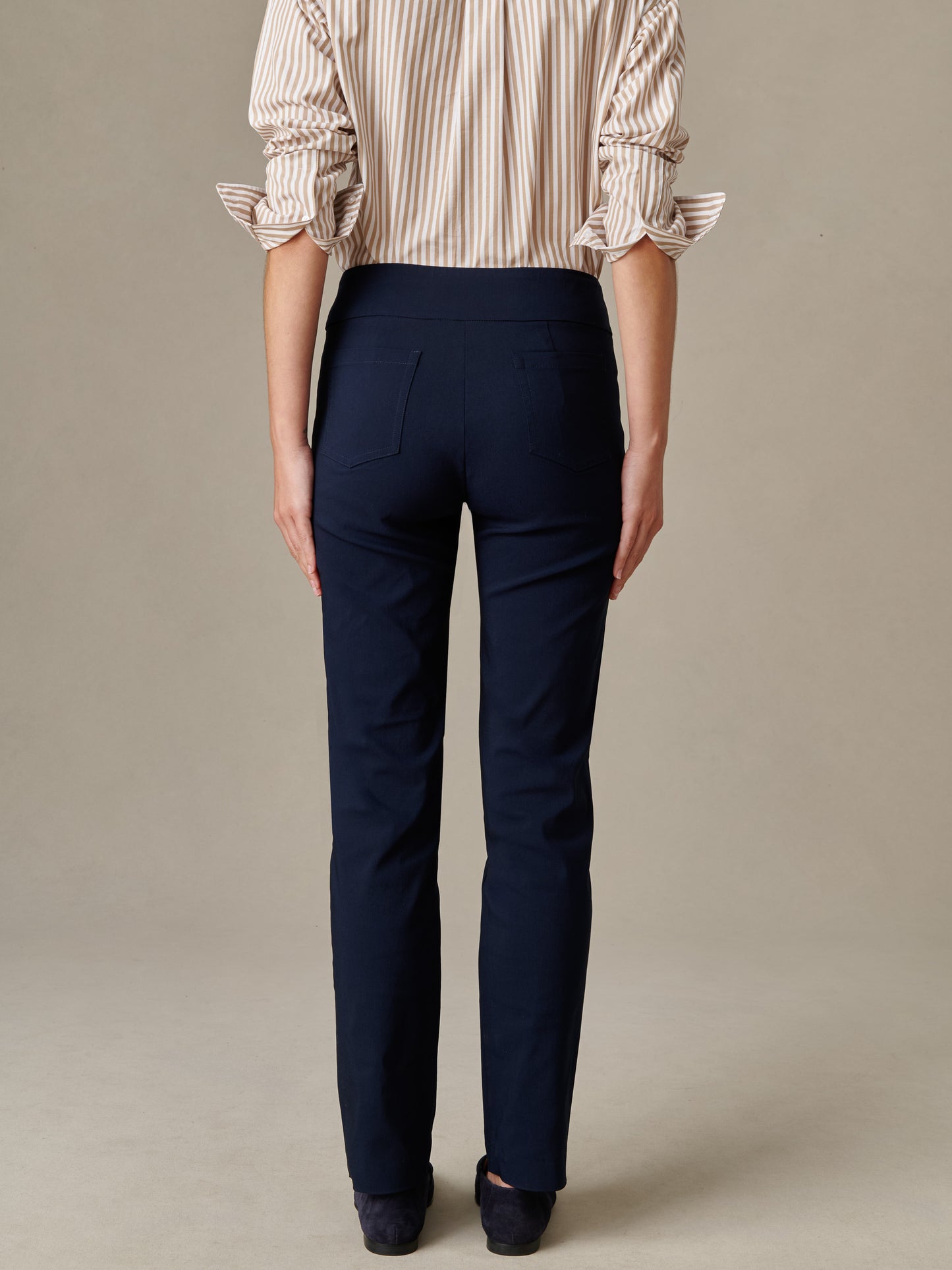 Back view of a person wearing navy Masie Pants by J.McLaughlin paired with a beige striped blouse, showcasing a sleek, effortlessly stylish look with enduring design quality.