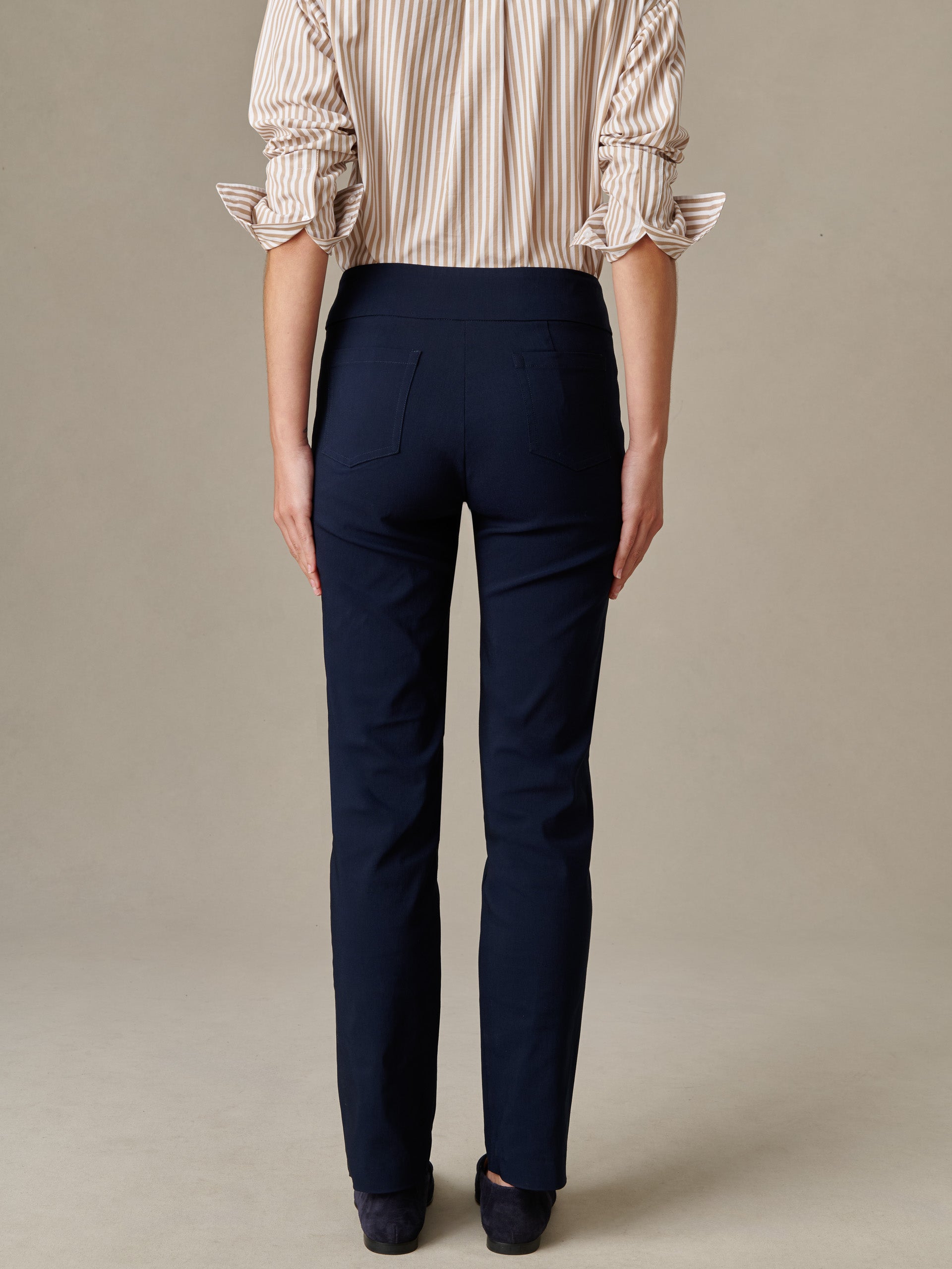 Back view of a person wearing navy Masie Pants by J.McLaughlin paired with a beige striped blouse, showcasing a sleek, effortlessly stylish look with enduring design quality.