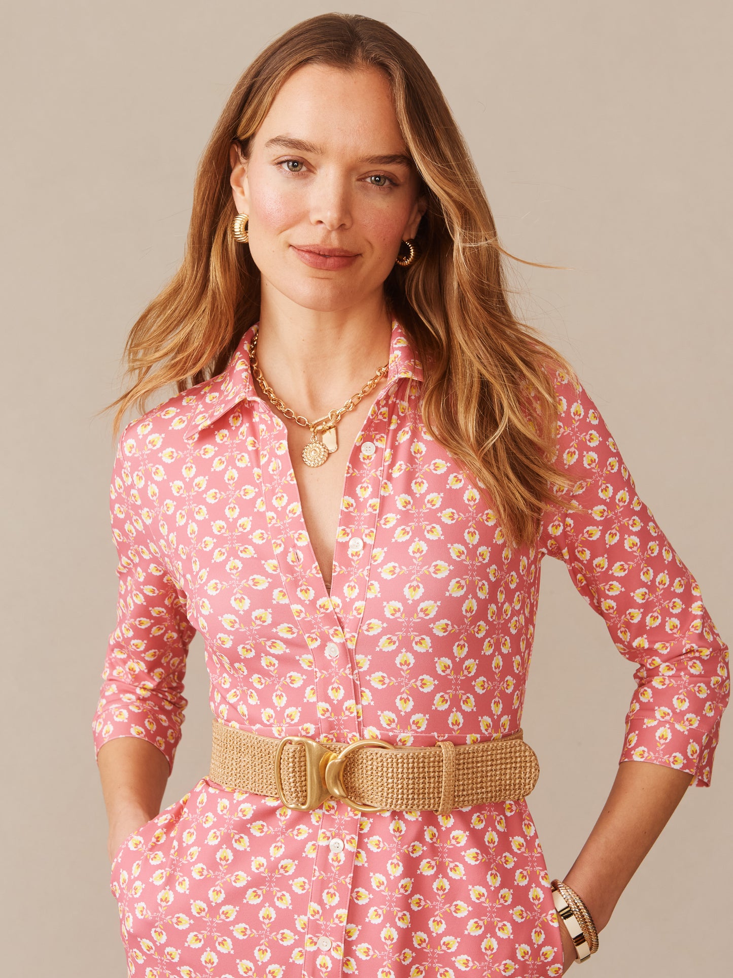 Woman wearing a Kailyn Maxi Dress in Mythic Floral Geo by J.McLaughlin featuring a pink floral pattern, paired with a woven belt and gold jewelry, embodying effortlessly stylish, enduring designs and innovative fabrics from a destination for defining style. Life, Well-Lived.