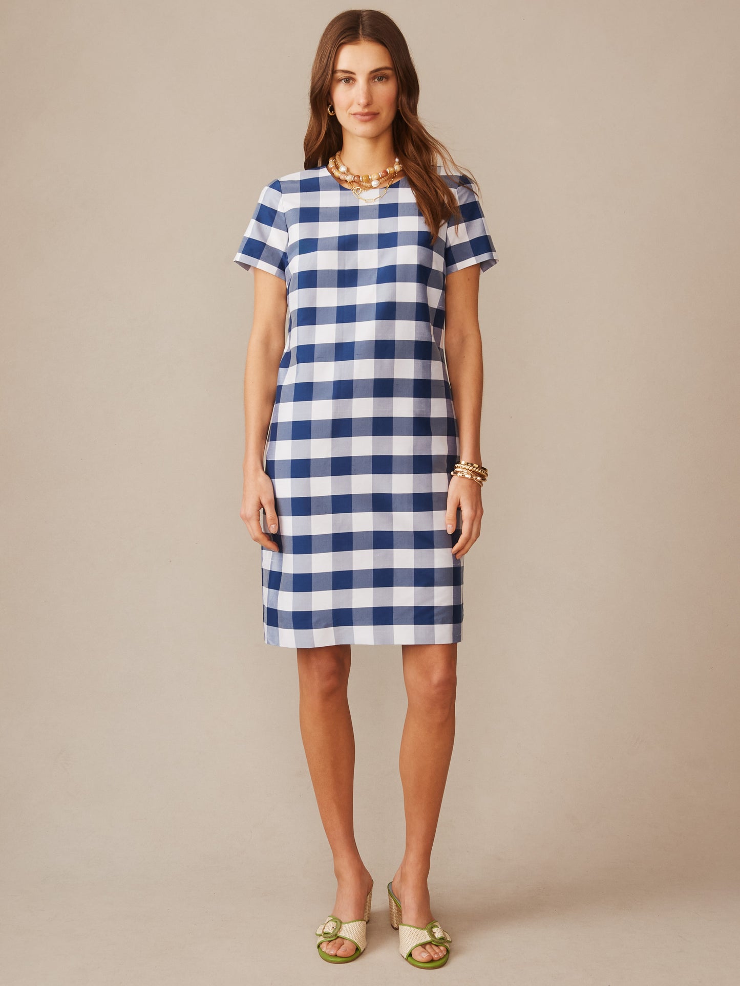 A woman wearing the Scarlett Silk Blend Dress in Gingham by J.McLaughlin featuring a classic blue and white check pattern, embodying effortlessly stylish, enduring designs with innovative fabrics and a legacy of timeless fashion. A destination for defining style. Life, Well-Lived.