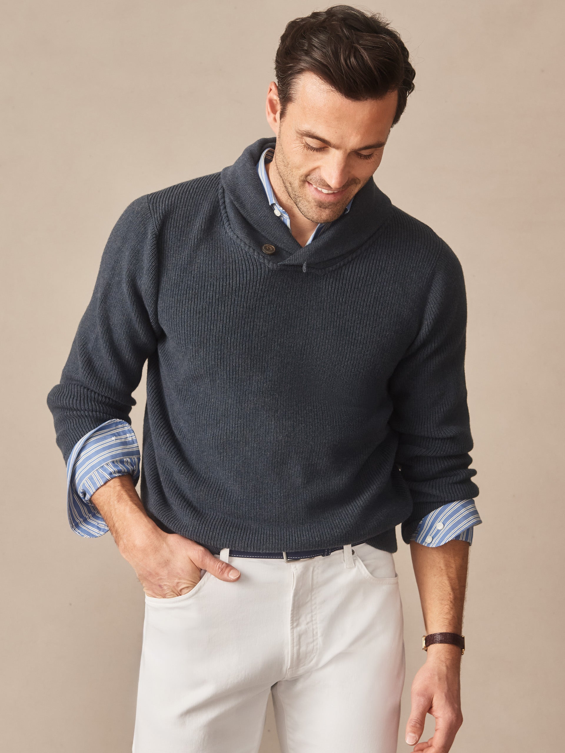 Man wearing a navy Hudson Sweater over a blue striped shirt paired with white pants, showcasing J.McLaughlin’s effortlessly stylish, enduring designs crafted from innovative fabrics.