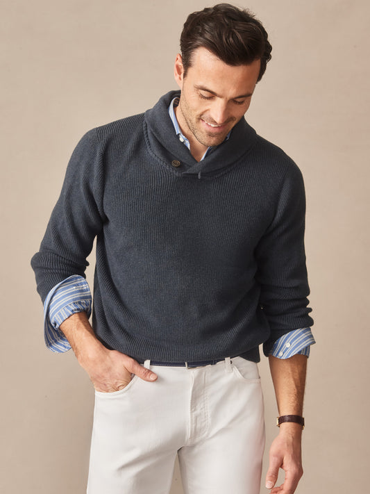 Man wearing a navy Hudson Sweater over a blue striped shirt paired with white pants, showcasing J.McLaughlin’s effortlessly stylish, enduring designs crafted from innovative fabrics.
