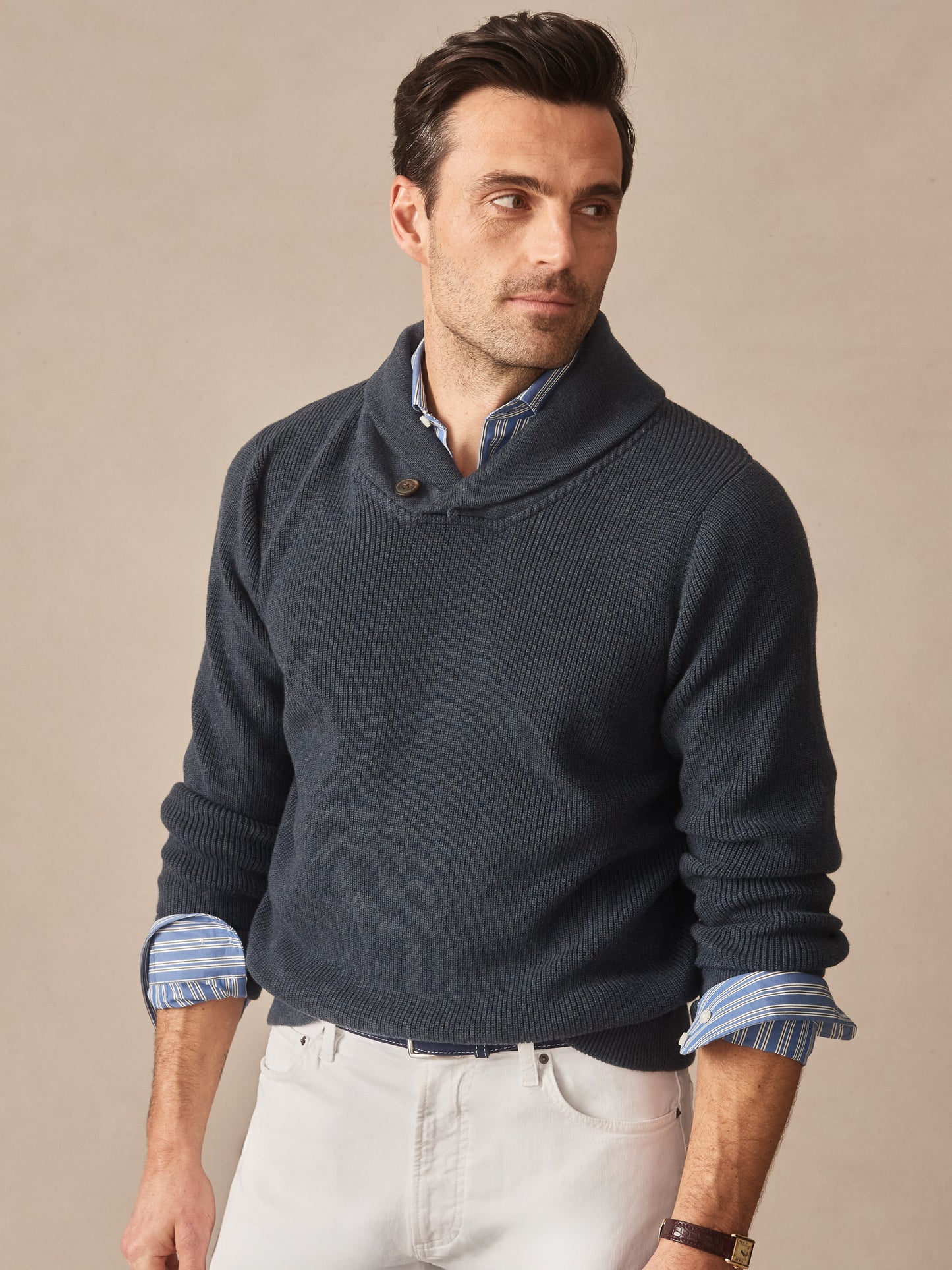 Man wearing a navy Hudson Sweater by J.McLaughlin layered over a blue striped shirt, showcasing effortlessly stylish, enduring designs crafted with innovative fabrics.