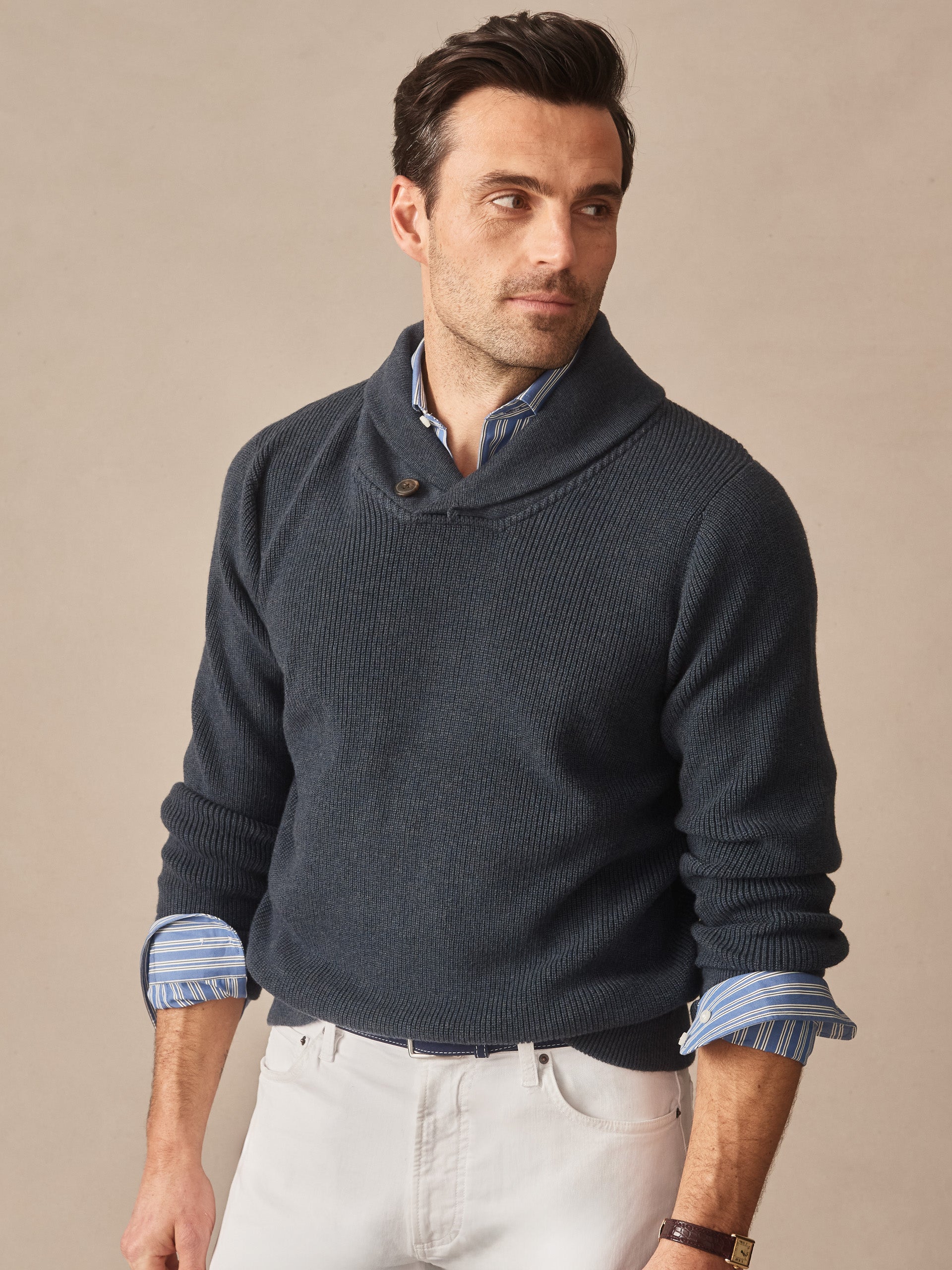 Man wearing a navy Hudson Sweater by J.McLaughlin layered over a blue striped shirt, showcasing effortlessly stylish, enduring designs crafted with innovative fabrics.