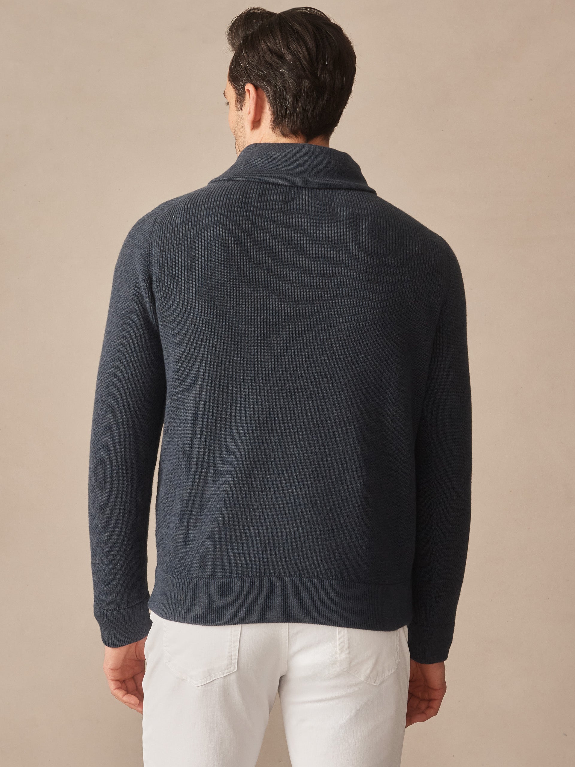 Man wearing a dark blue Hudson Sweater by J.McLaughlin, showcasing effortlessly stylish knitwear with enduring designs crafted from innovative fabrics, embodying a legacy of timeless fashion.