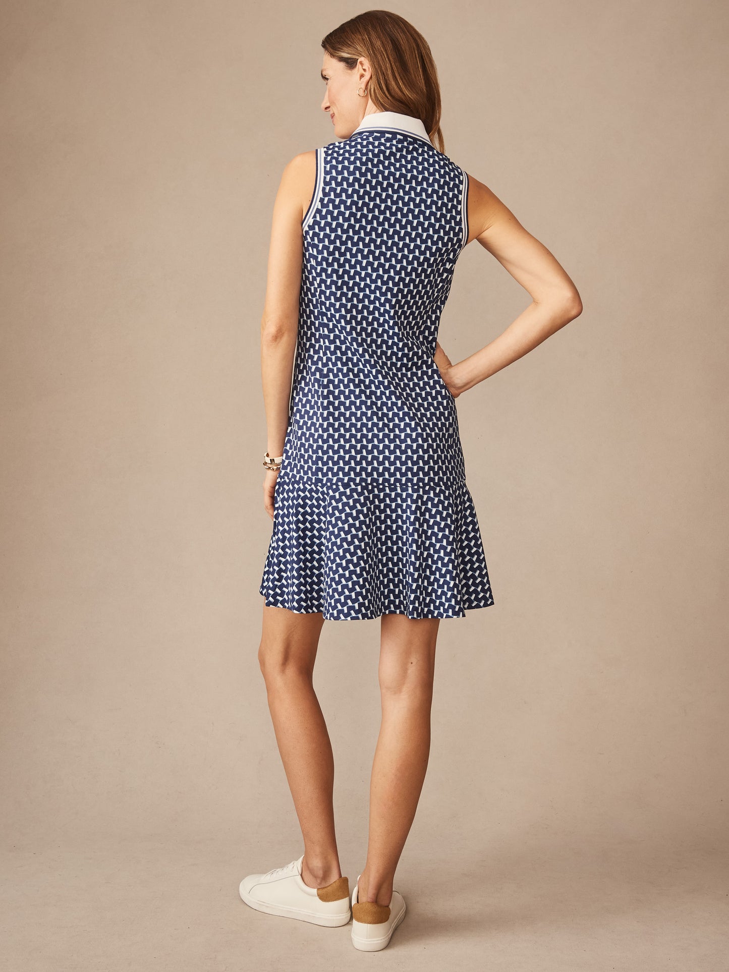 Woman wearing a sleeveless Merlin Dress in Duncan by J.McLaughlin, featuring a navy and light blue pattern, styled with white sneakers for an effortlessly stylish look, embodying enduring designs and innovative fabrics. A destination for defining style. Life, Well-Lived.