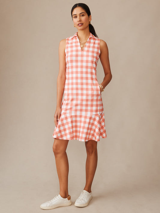 Woman wearing a sleeveless Merlin Dress in Textured Gingham by J.McLaughlin in soft coral and white, styled effortlessly with simple jewelry and white sneakers, showcasing enduring designs and innovative fabrics from a destination for defining style. Life, Well-Lived.