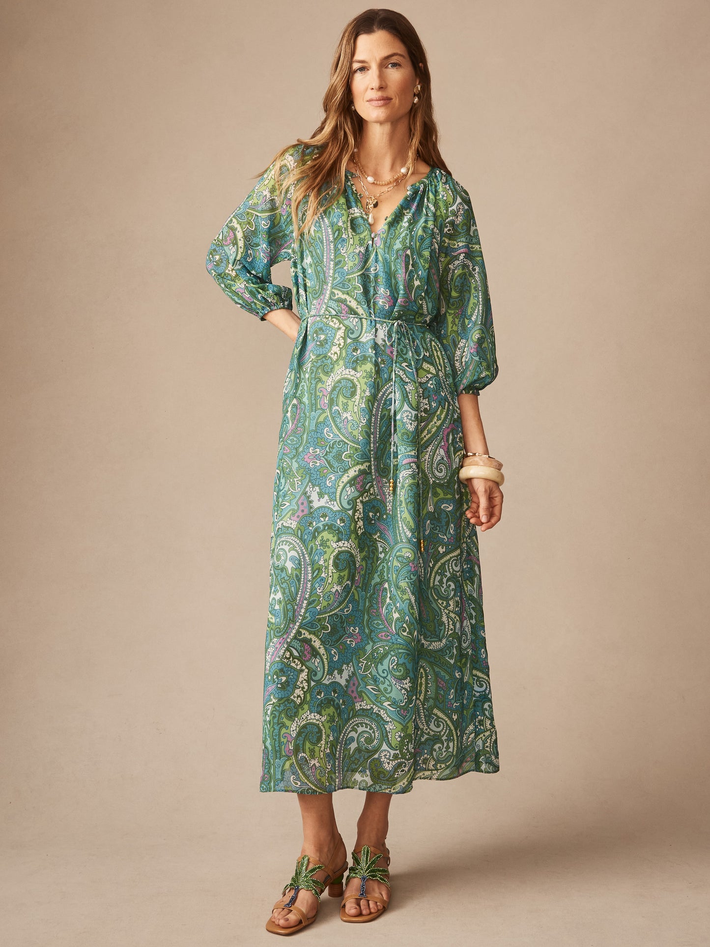 A woman models the Mia Dress in Paisley Reverie by J.McLaughlin, featuring an effortlessly stylish paisley pattern in green and blue tones with enduring designs and elegant silhouette.
