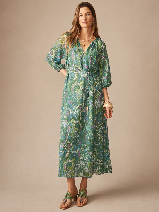 A woman models the Mia Dress in Paisley Reverie by J.McLaughlin, featuring an effortlessly stylish paisley pattern in green and blue tones with enduring designs and elegant silhouette.