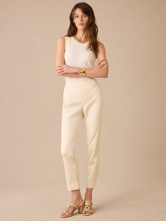 A woman wearing cream Millbrook Dupioni Cotton Pants by J.McLaughlin paired with a sleeveless top and gold accessories, showcasing effortlessly stylish and enduring designs.