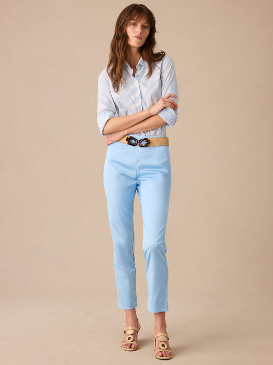 Woman wearing Millbrook Dupioni Cotton Pants in light blue by J.McLaughlin paired with a striped button-up shirt and beige belt, showcasing effortlessly stylish, enduring designs and innovative fabrics.
