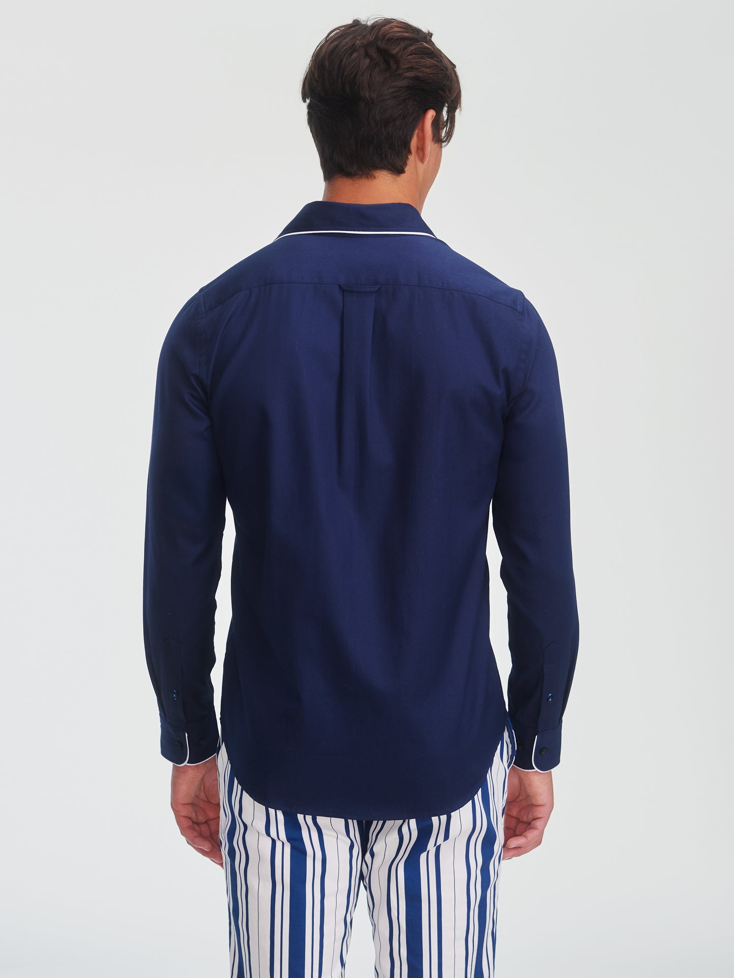 Man wearing a navy Anderson Cotton Shirt by J.McLaughlin paired with blue and white striped pants, showcasing effortlessly stylish, enduring designs and innovative fabrics.
