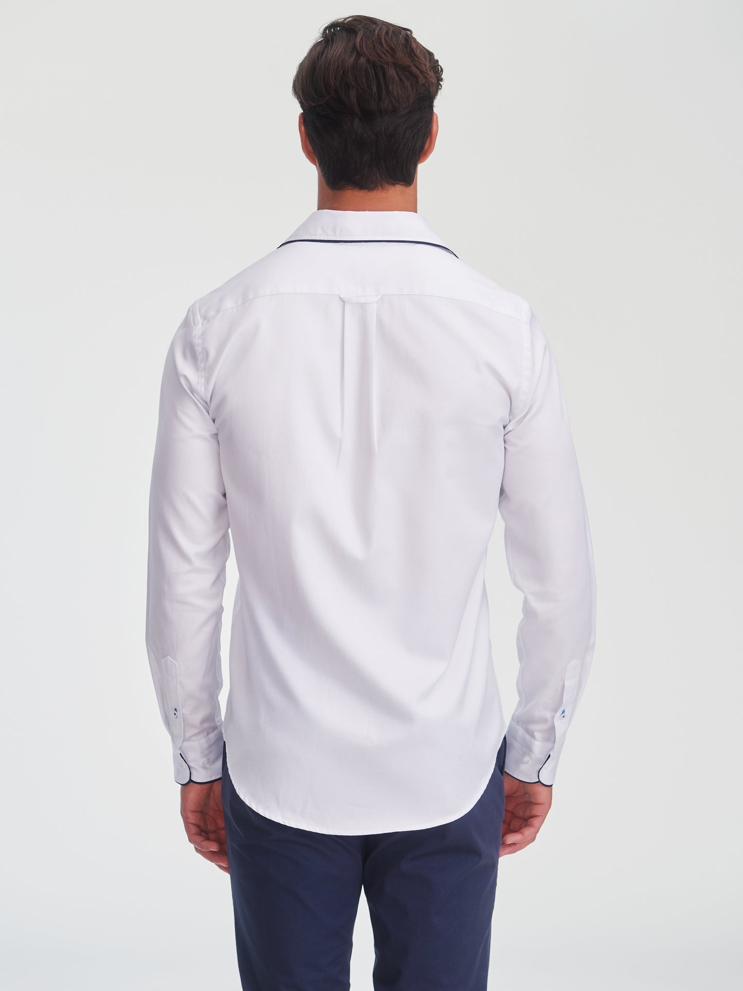 Man wearing a white Anderson Cotton Shirt by J.McLaughlin, showcasing an effortlessly stylish design with subtle detailing, embodying enduring designs and innovative fabrics.