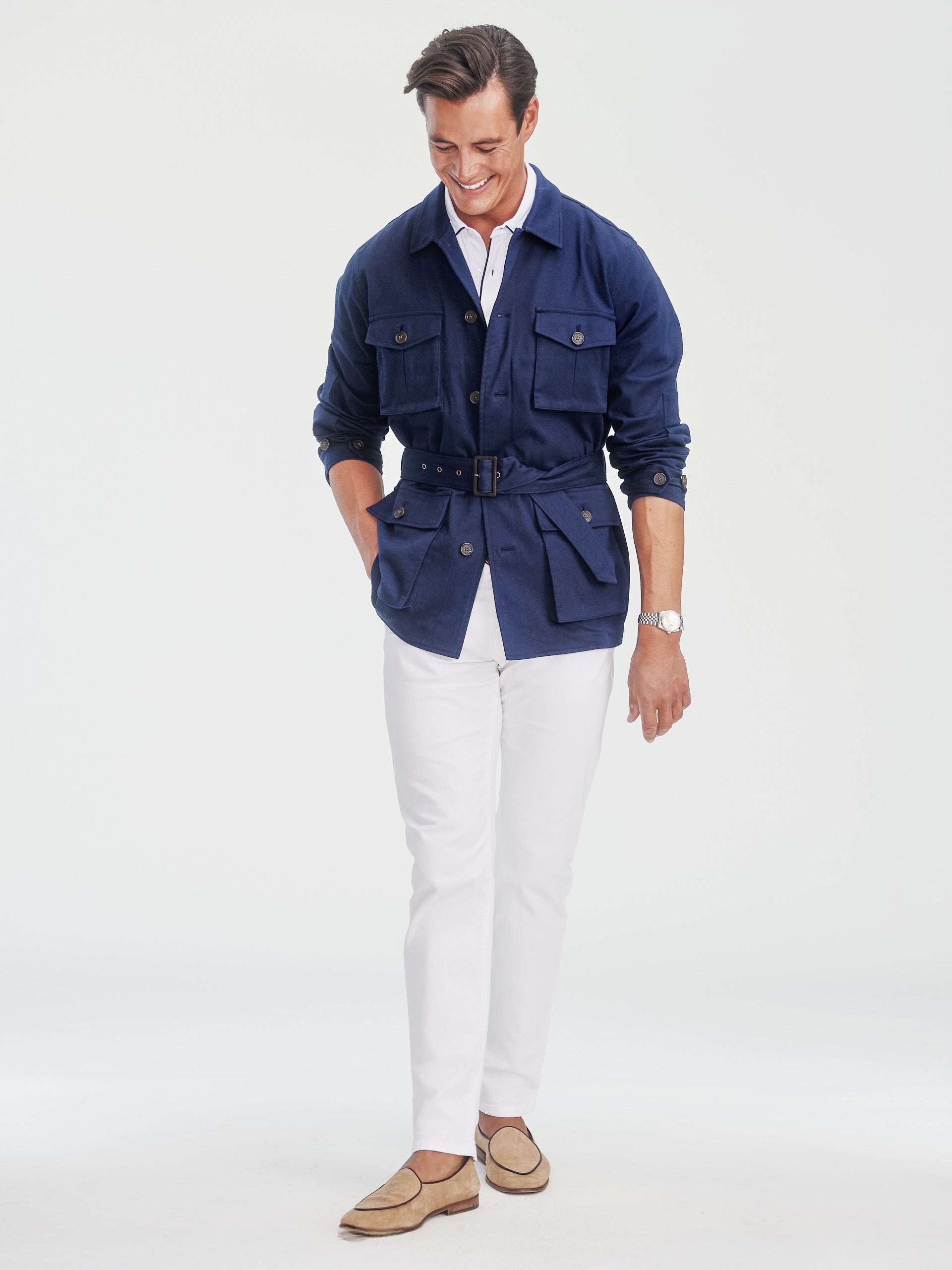 Man wearing a navy Michael Jacket by J.McLaughlin paired with white pants and beige loafers, showcasing effortlessly stylish outerwear with enduring designs and a timeless look.