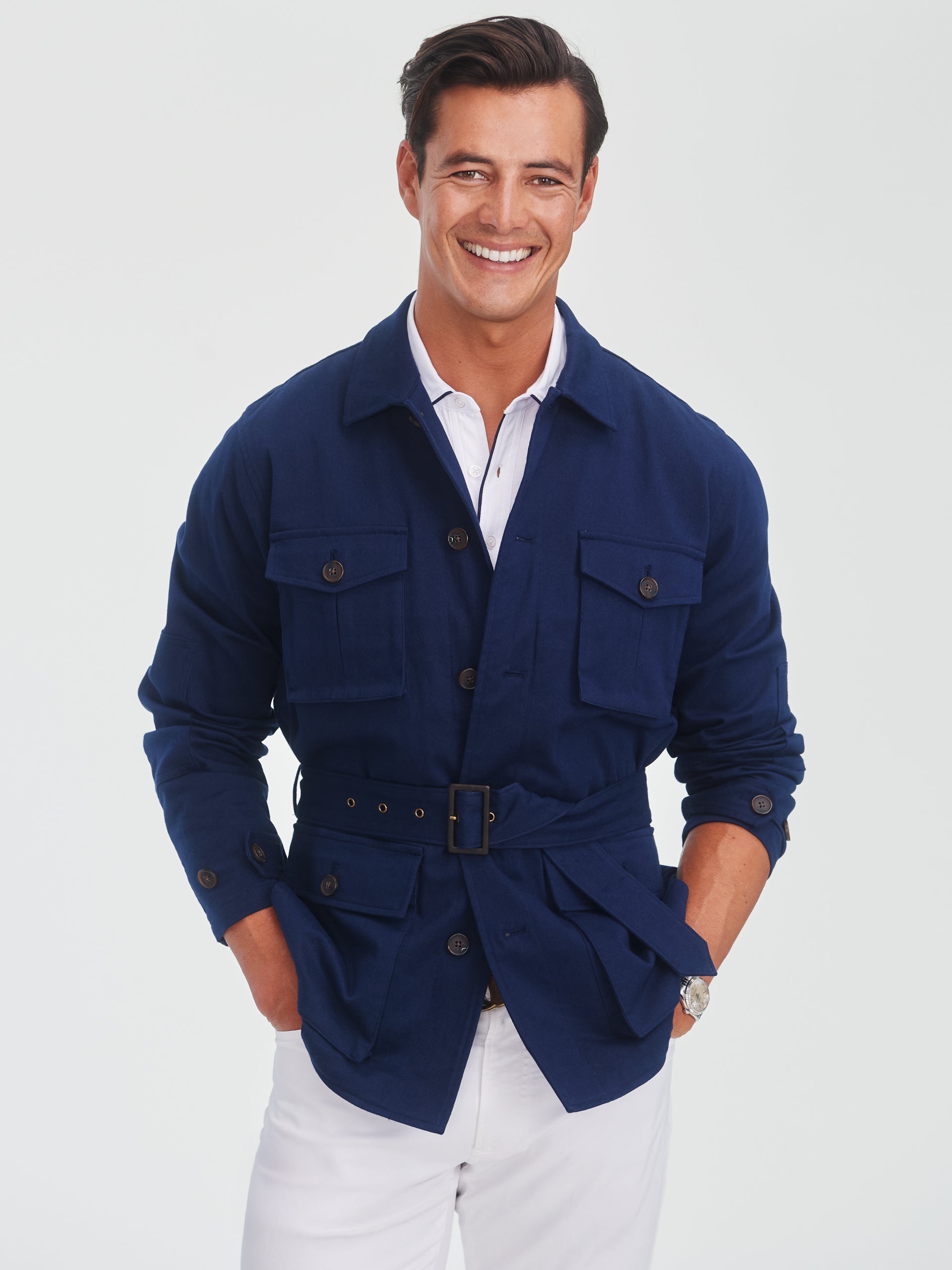 Man wearing a navy Michael Jacket by J.McLaughlin with a belted waist and buttoned pockets, showcasing effortlessly stylish design and enduring craftsmanship for a life well-lived.
